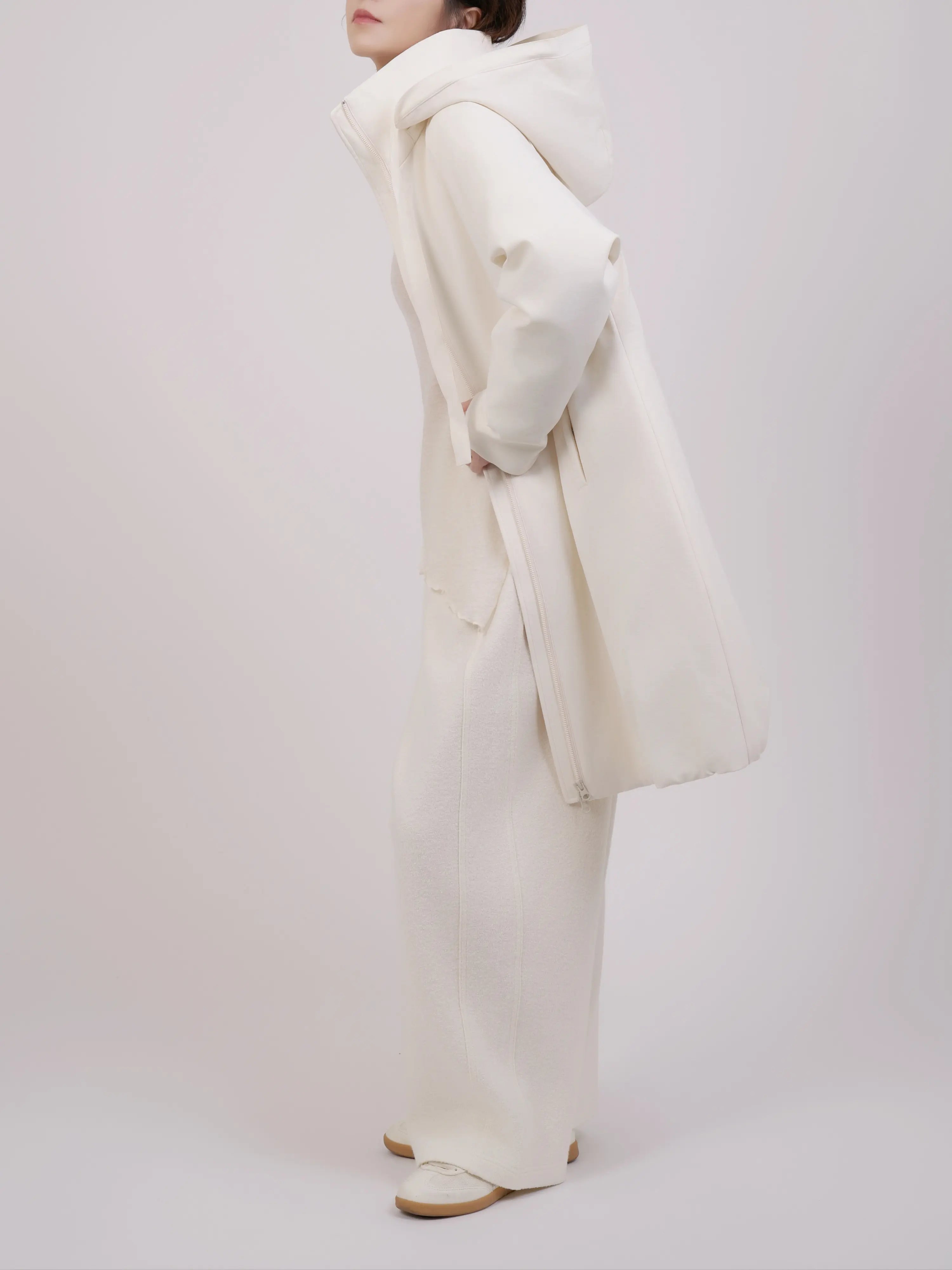 Side profile of off-white down coat showing hood structure and silhouette.