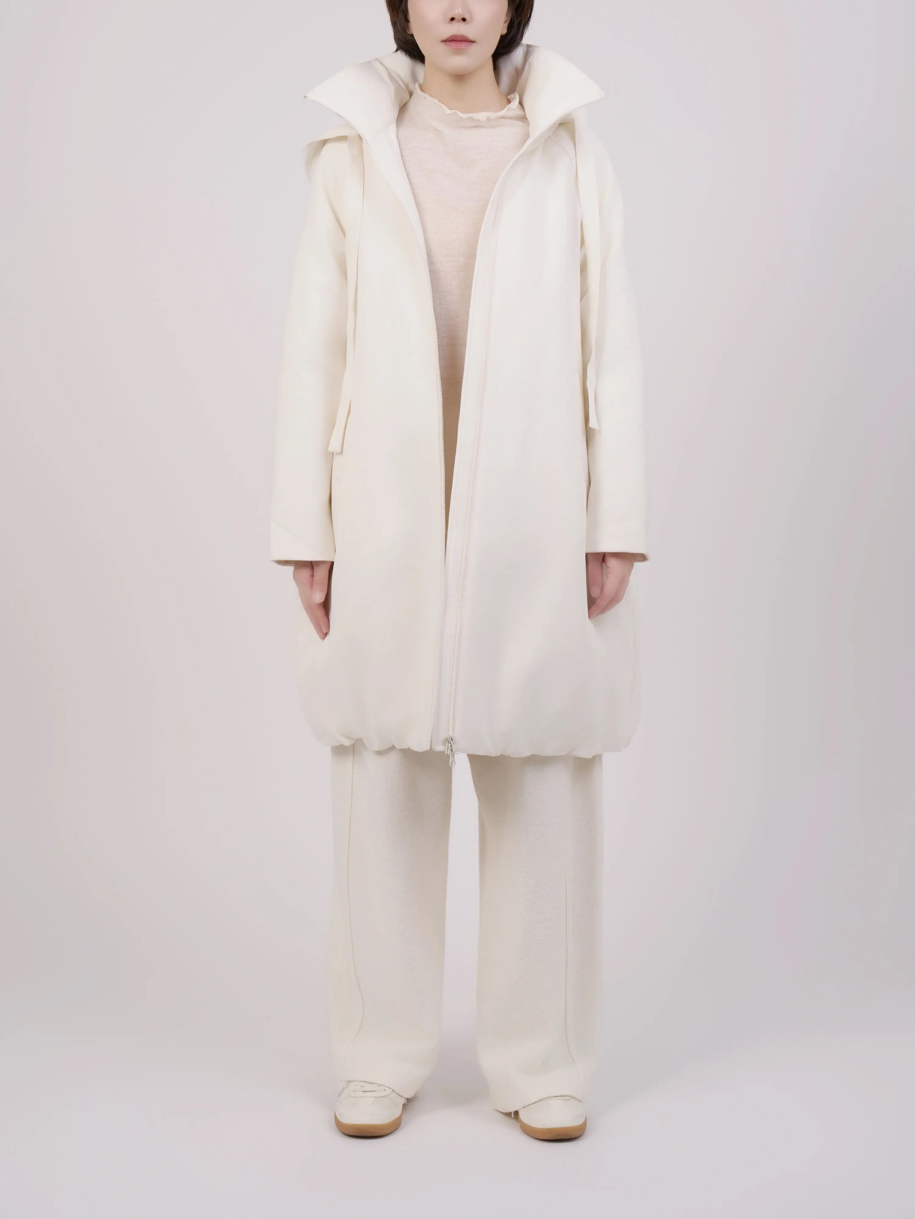 Full front view of off-white hooded down coat styled in a clean minimalist look.