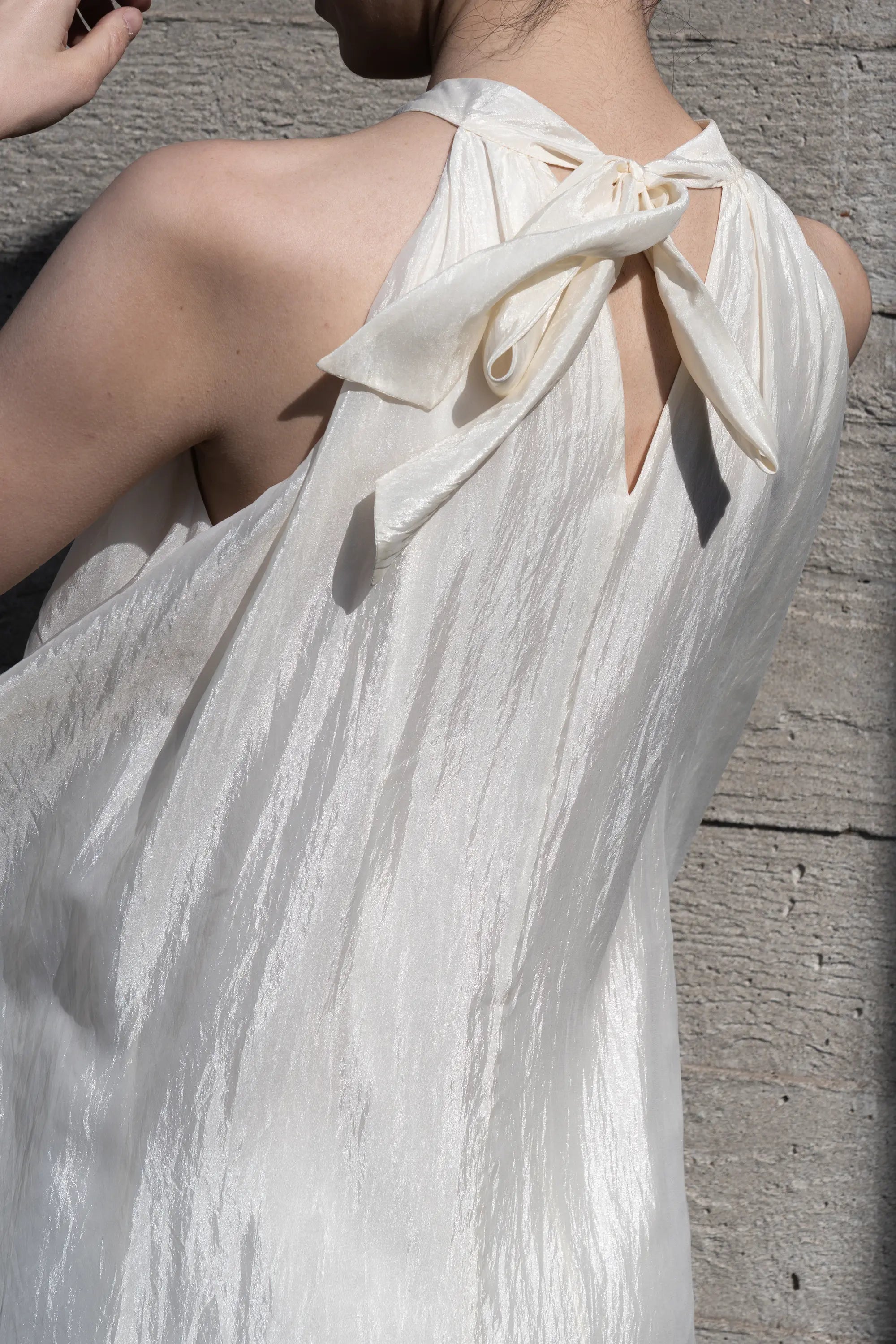 Close-up of halter neck tie detail on ivory maxi dress with soft texture