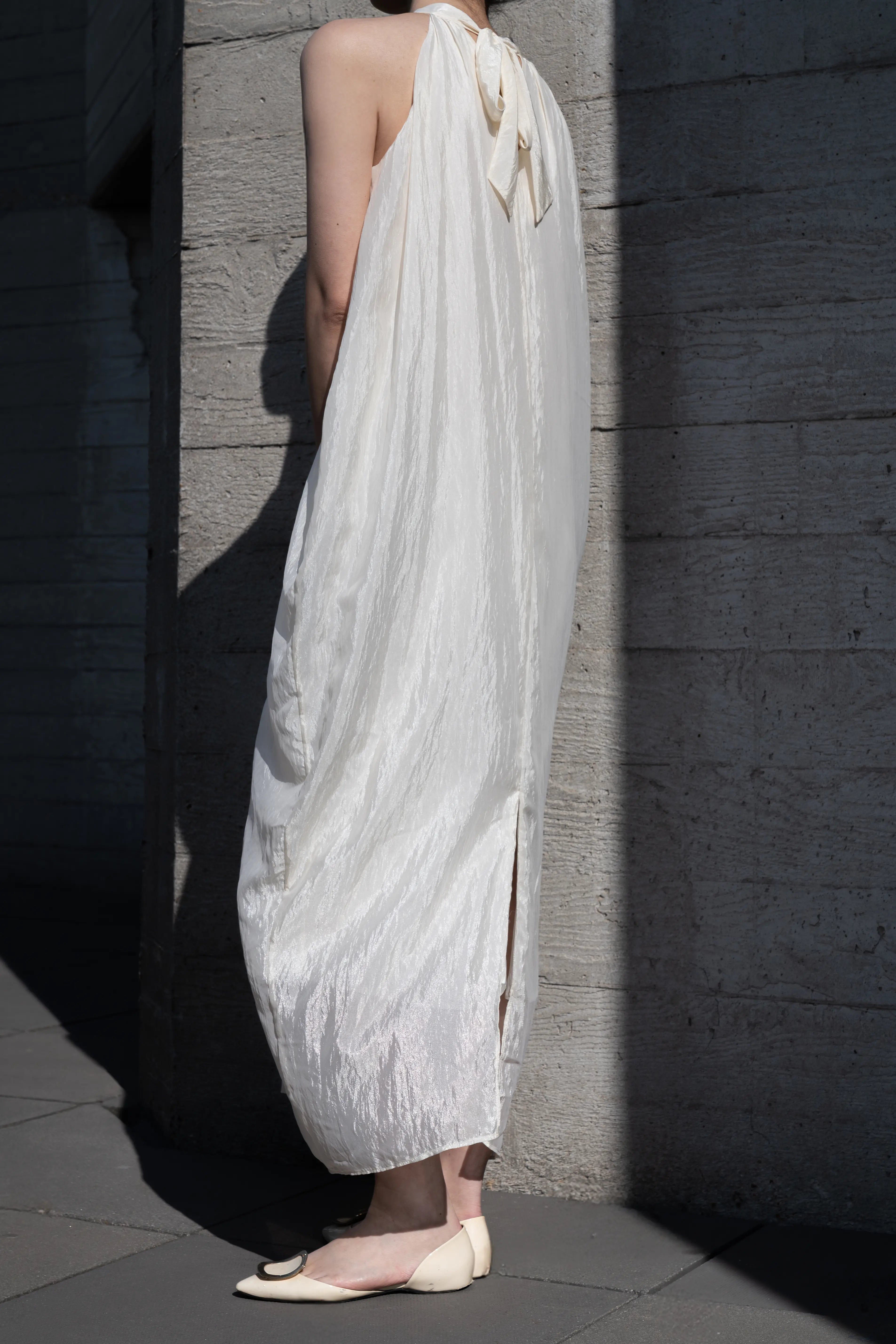 Side view of ivory halter-neck maxi dress showing fluid silhouette and relaxed fit