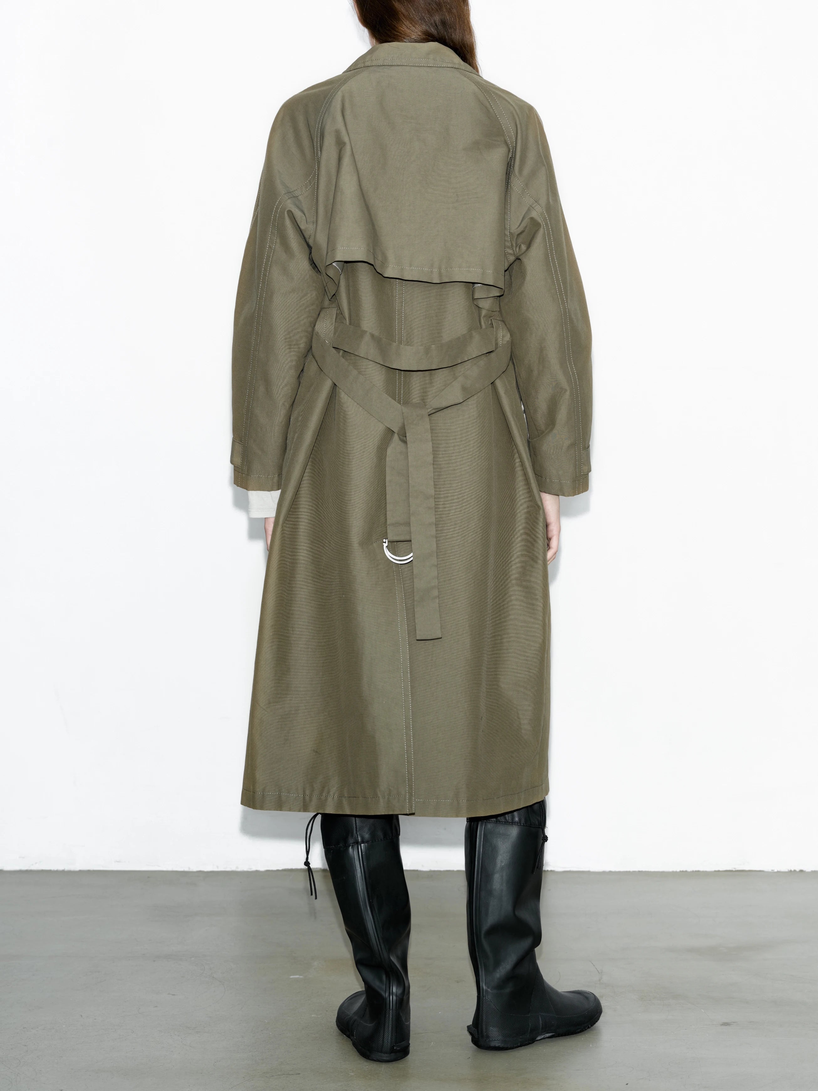 Back view army green trench coat showing layered back construction and belt detail, oversized silhouette