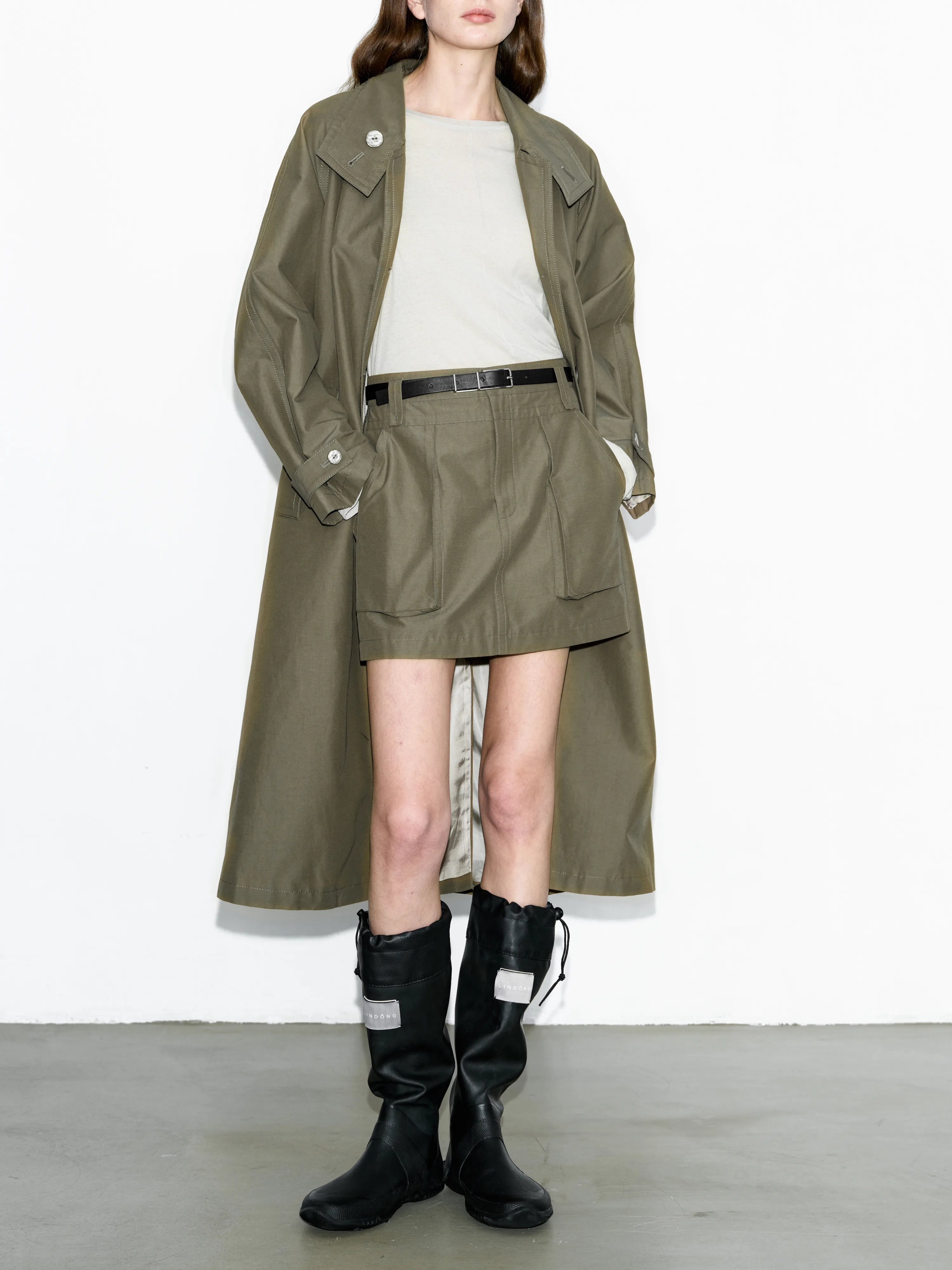 Front view army green trench coat styled casually with white top and boots, oversized cut with clean drape