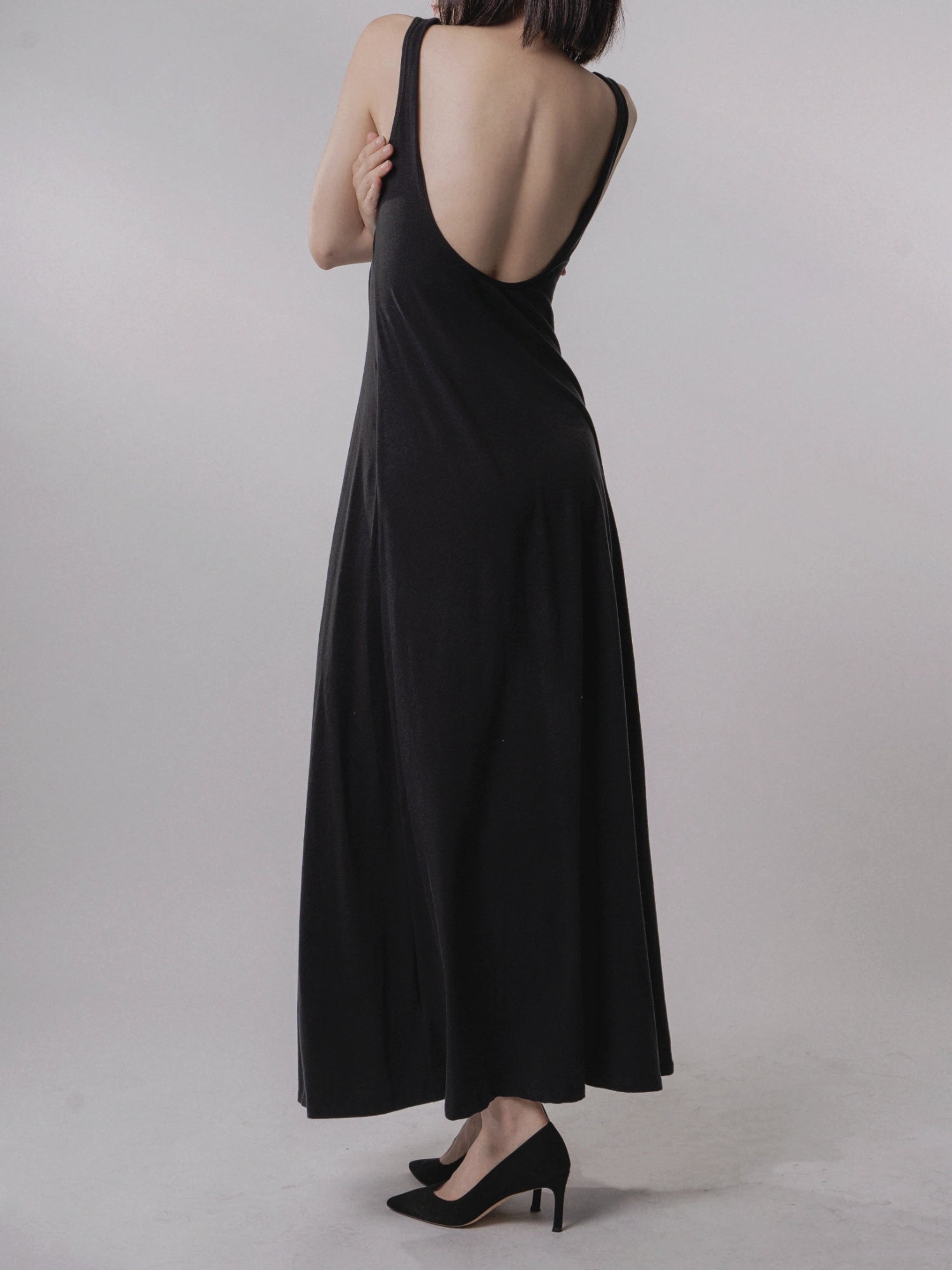 Backless black dress full-body view, open low back, minimalist evening silhouette, ankle length, slim fit for elegant styling.