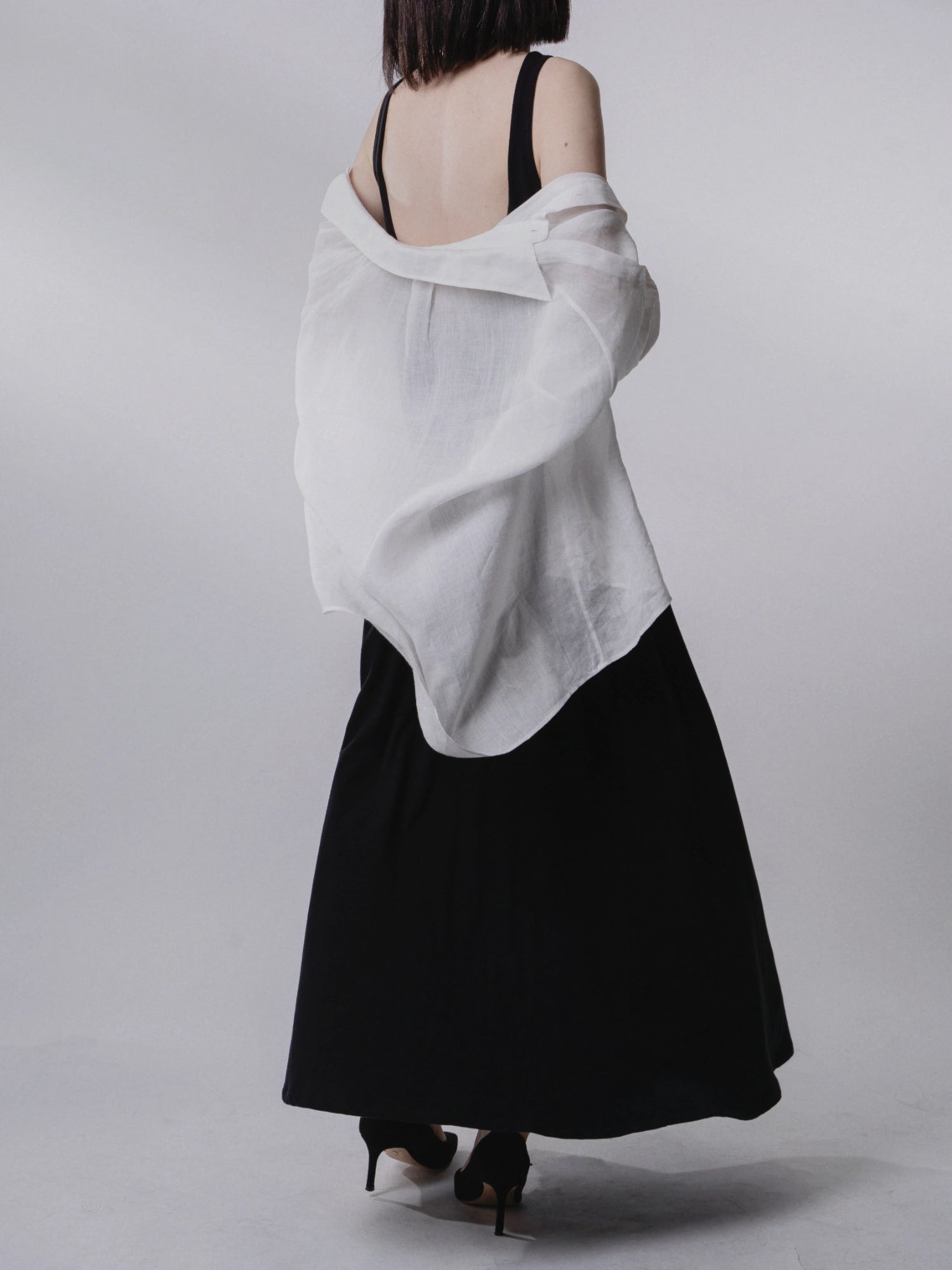 Backless dress styled with outer wrap, rear angle, movement and volume captured.