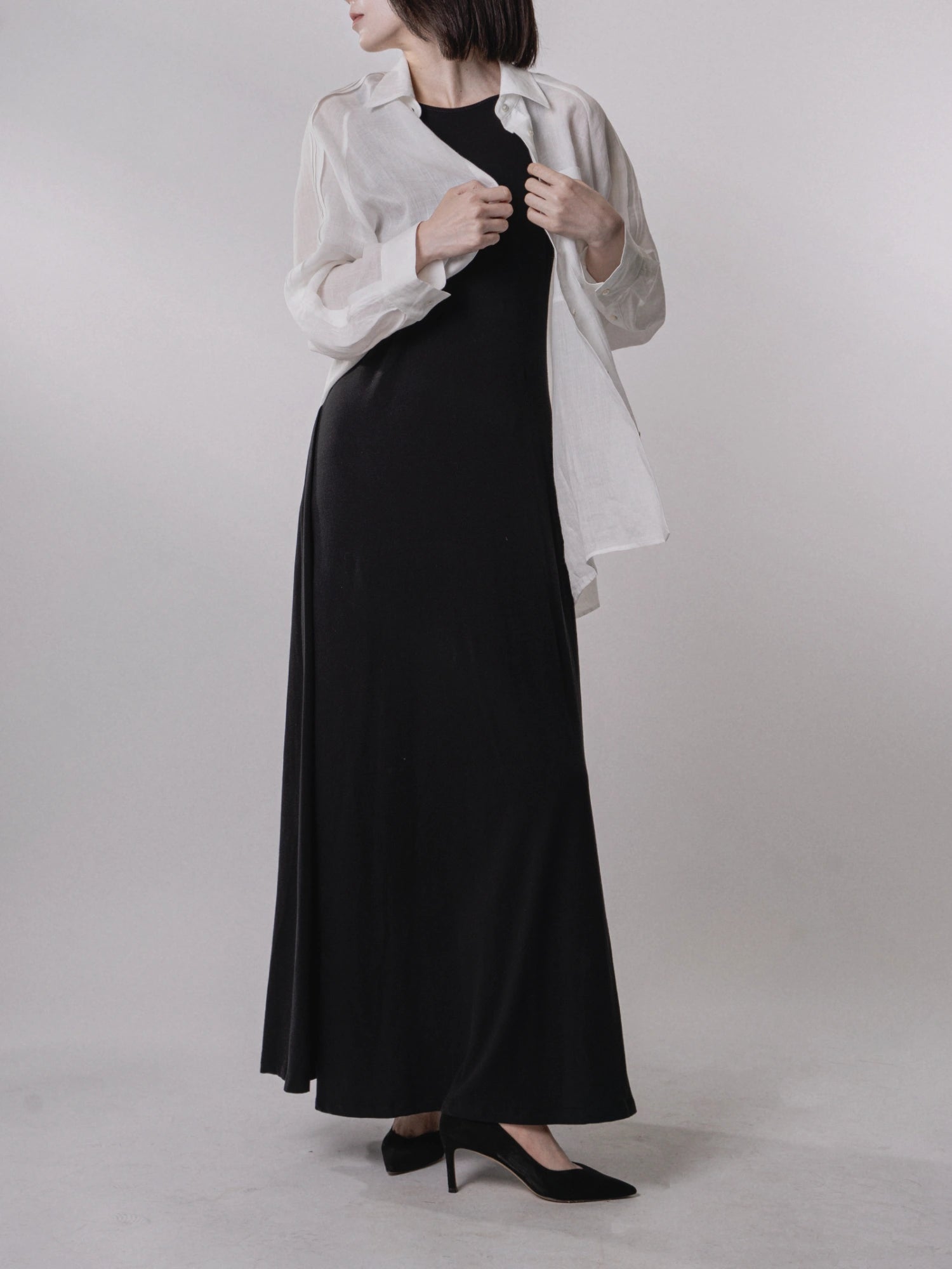 Layered styling with white shawl over black backless dress, modern contrast, soft drape.