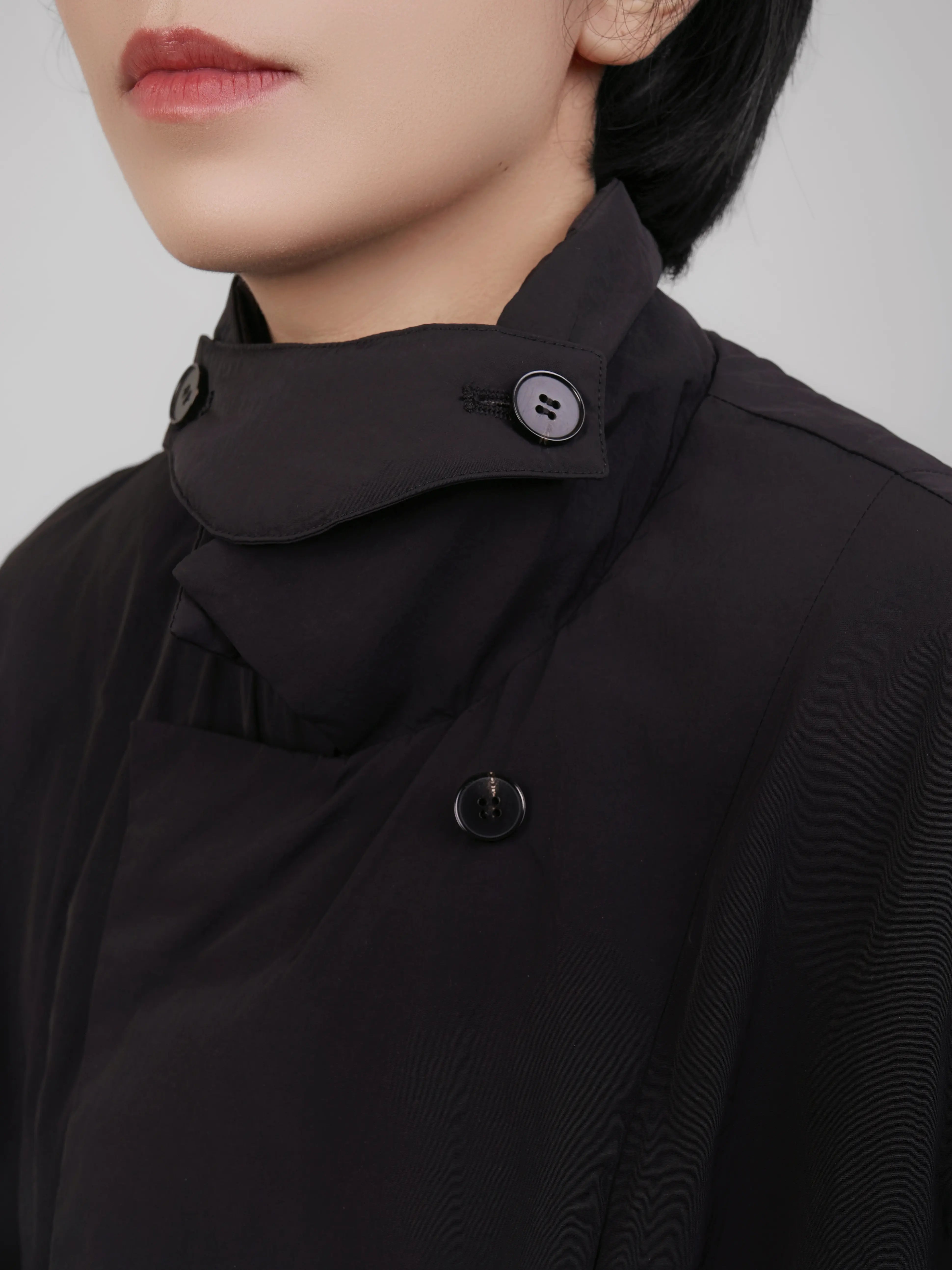 Close-up of collar and neckline showing high collar design and button detail.