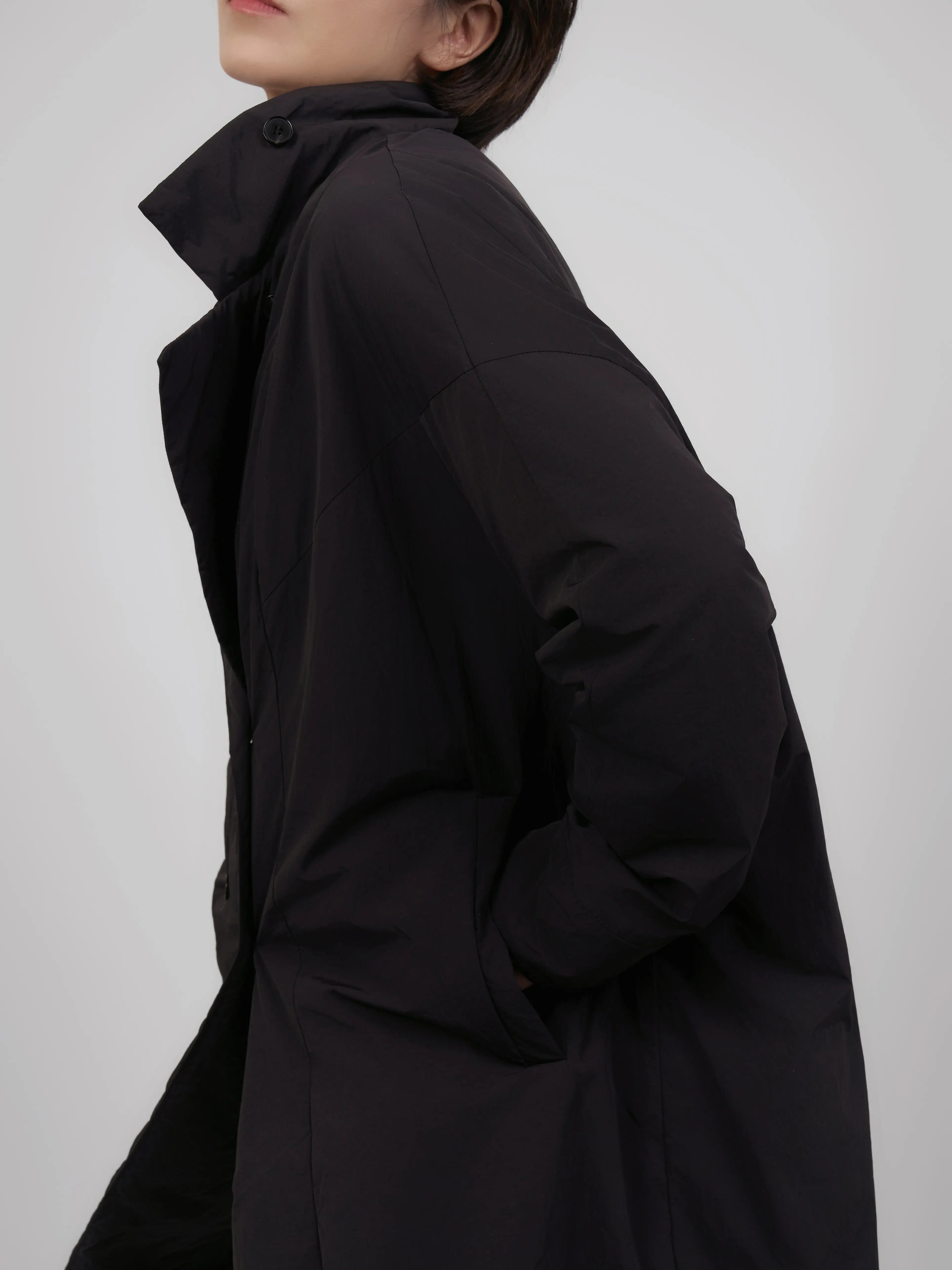 Side detail of oversized down coat showing volume, drape and pocket placement.