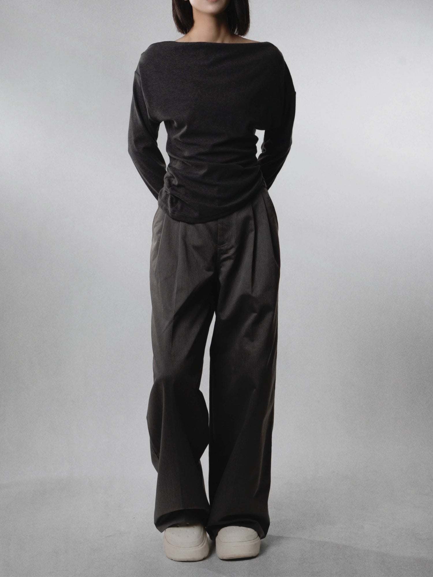 Front view of charcoal wide-leg trousers paired with black top, highlighting clean drape and elongated line