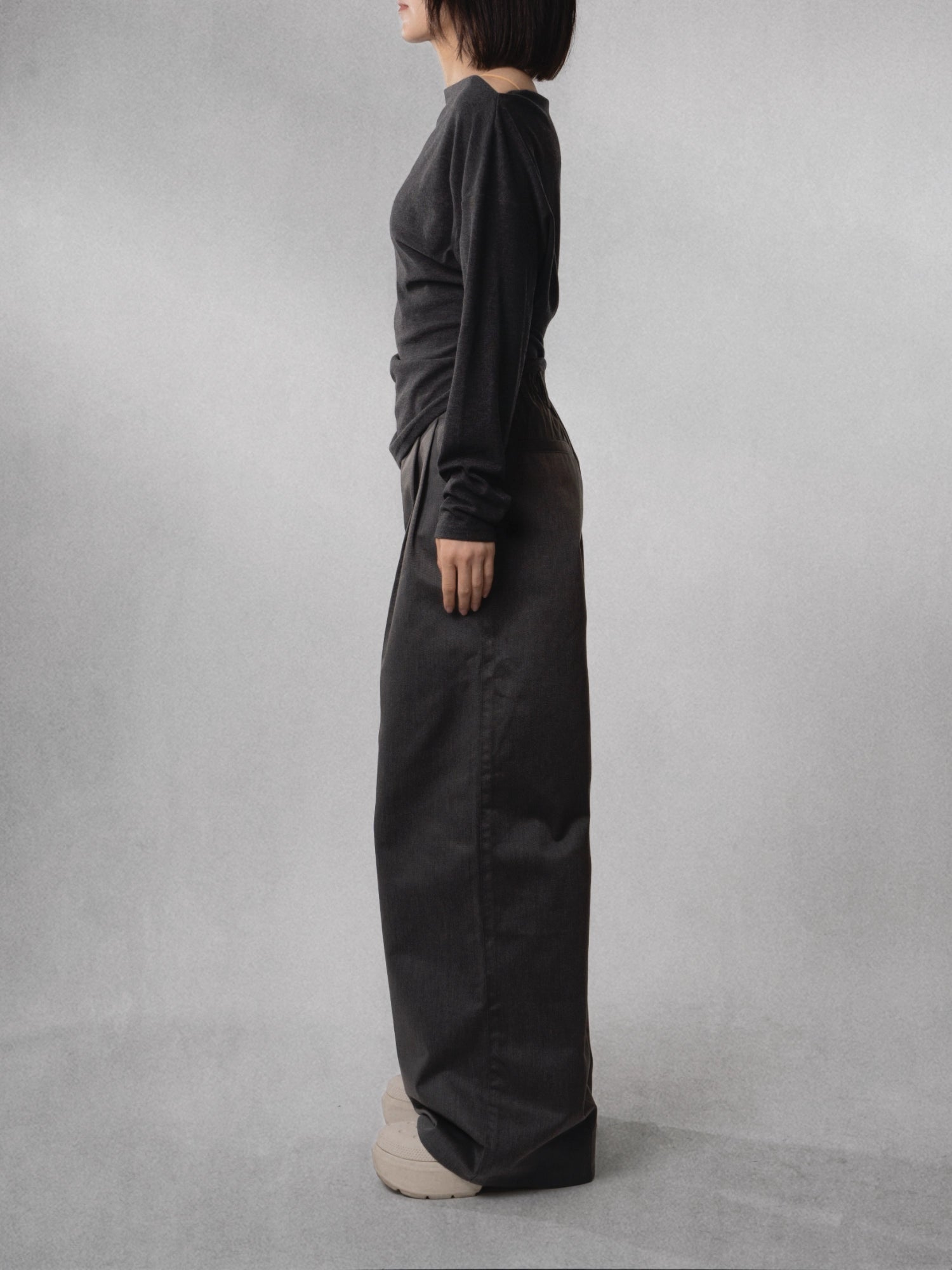 Slim side view of charcoal wide-leg trousers, highlighting clean straight fall and lightweight structure.
