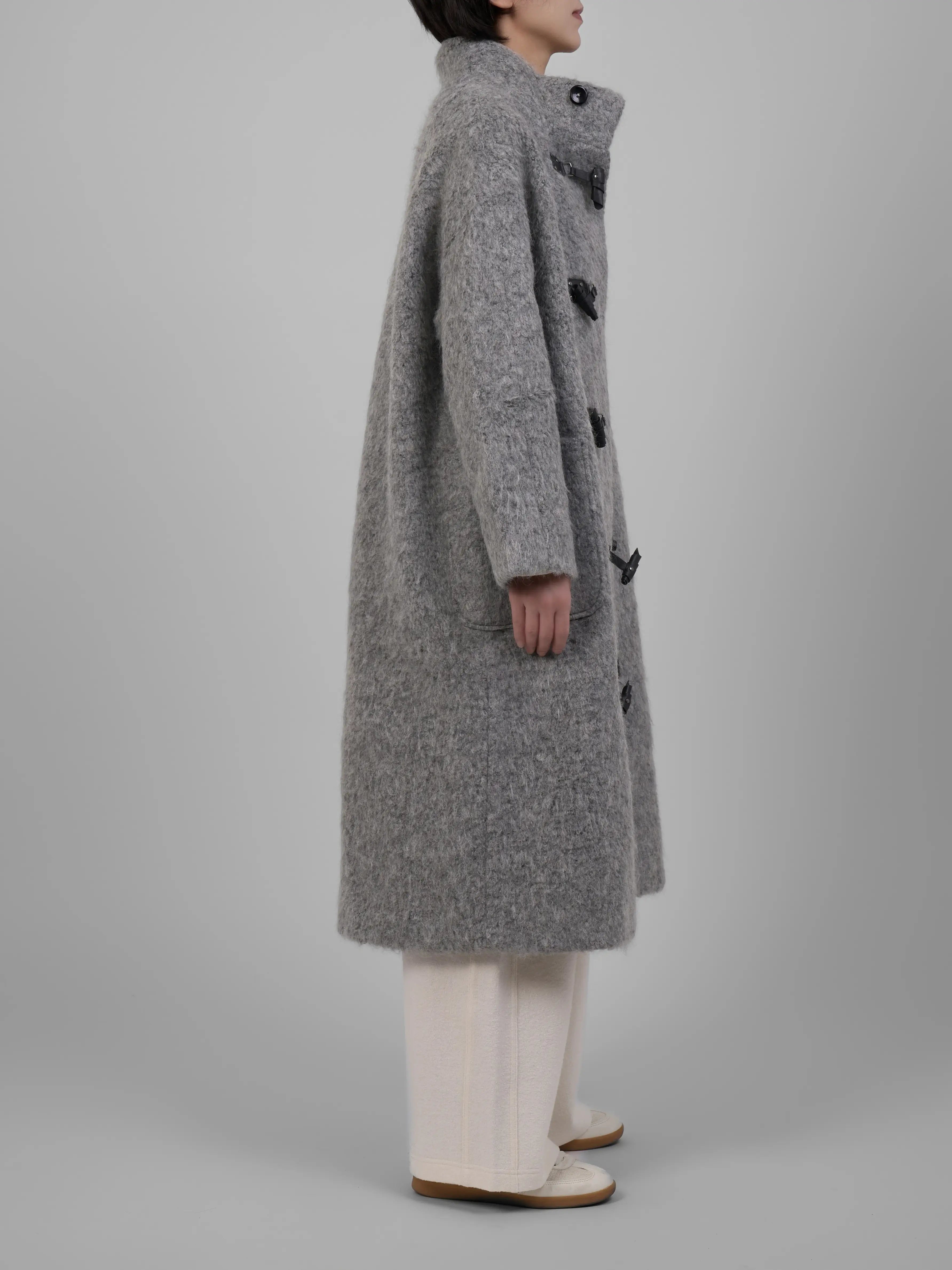 Angled view of XXLSMILE Grey Wool Toggle Coat showing pockets and natural drape.
