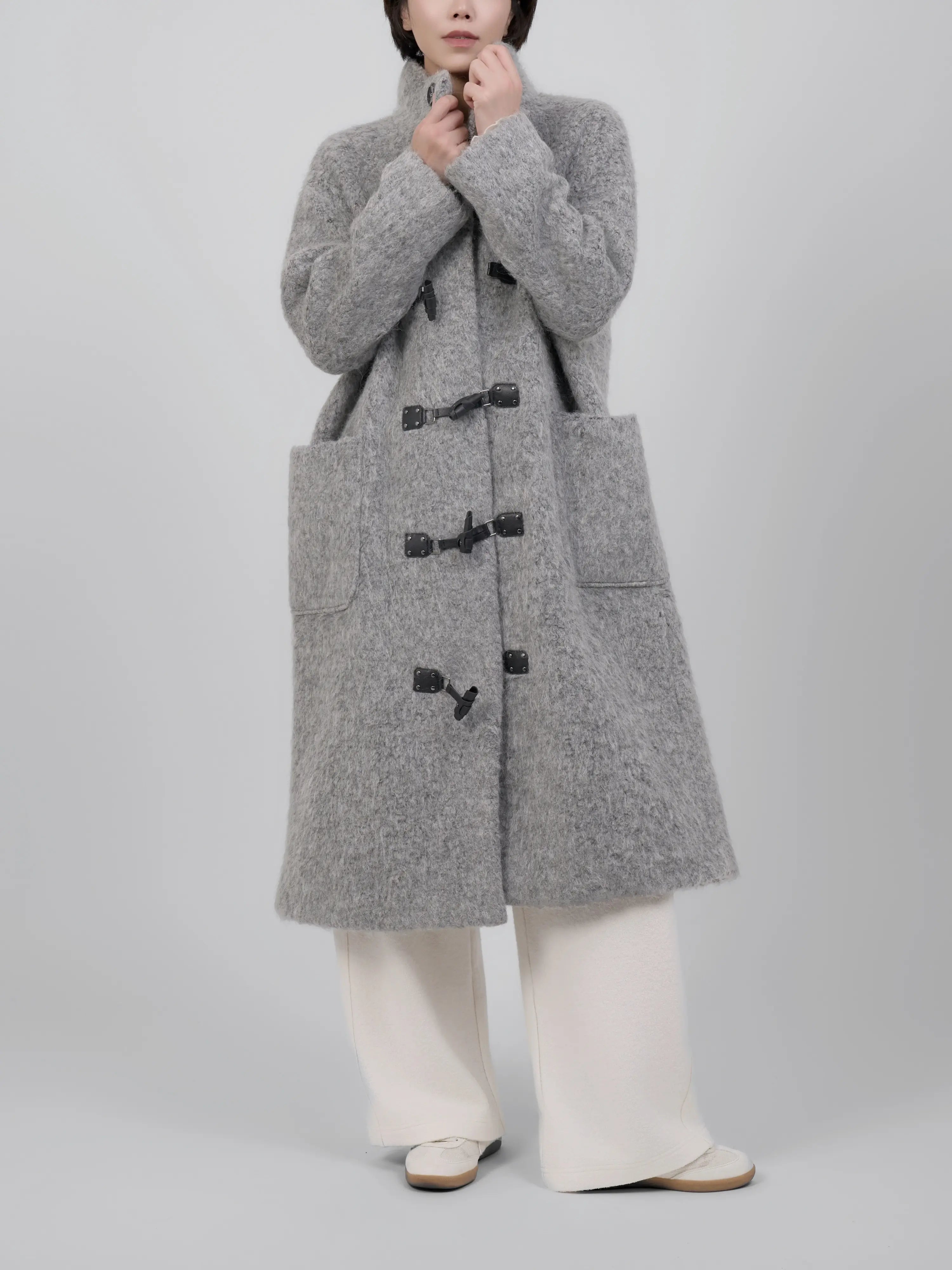 Front view of grey wool coat with toggle fastening and clean straight cut.