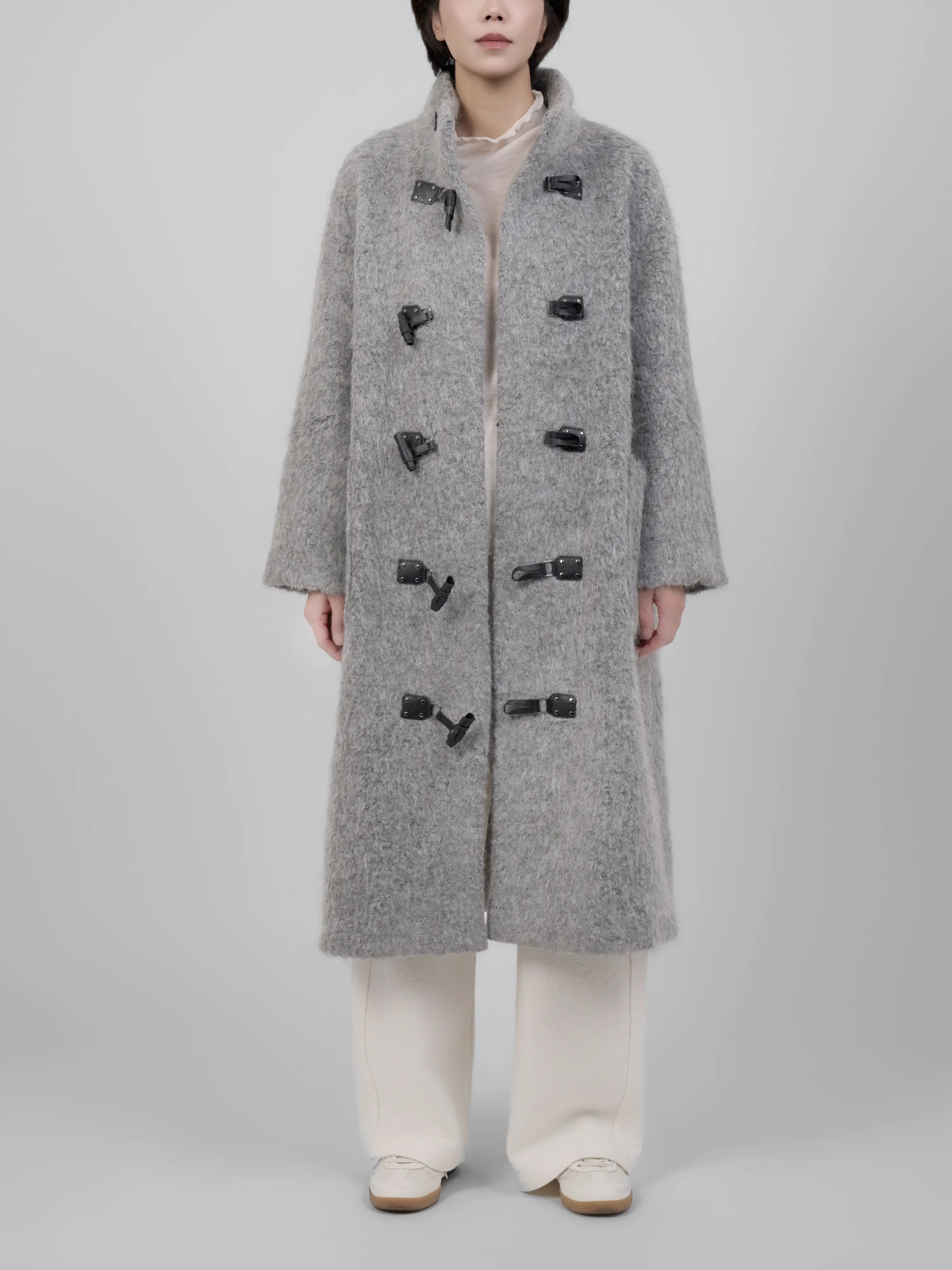 Full body look of grey wool toggle coat styled with wide-leg trousers, showing a relaxed winter silhouette.