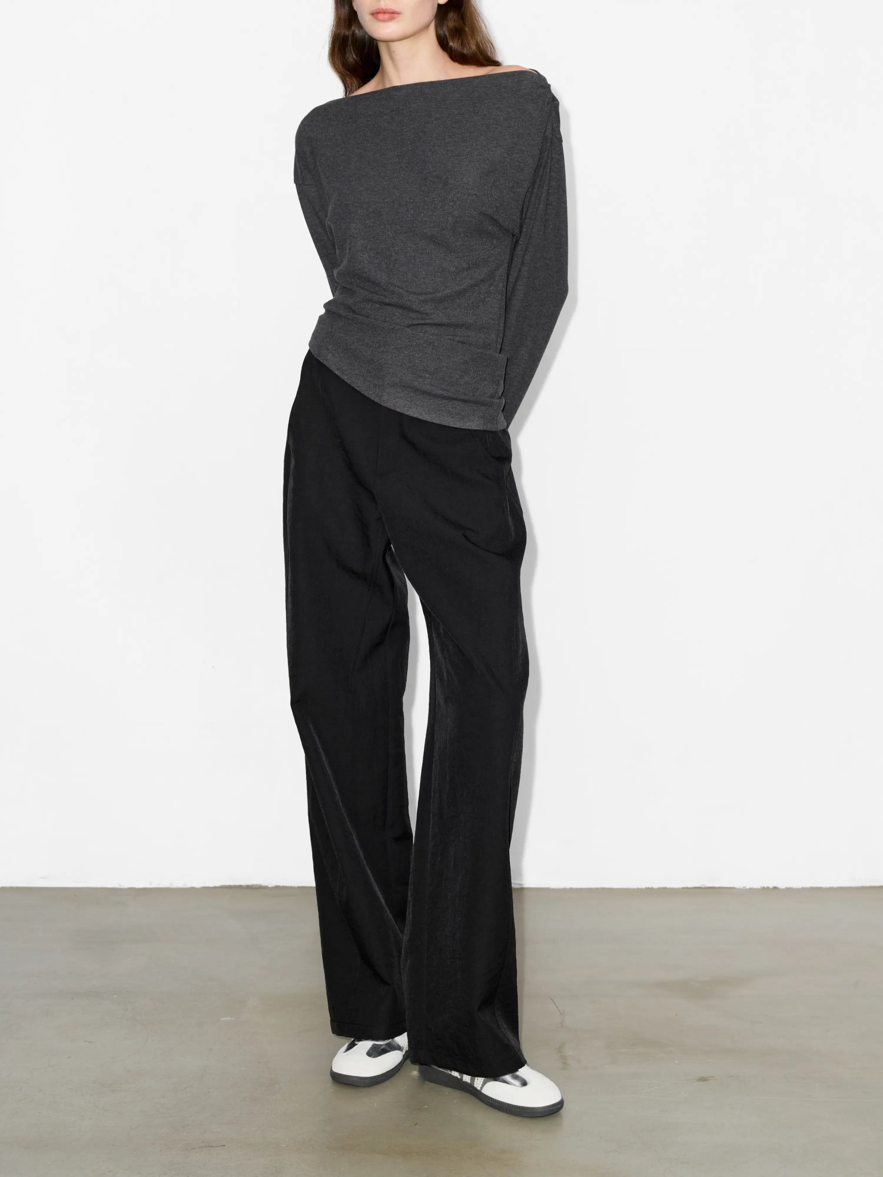 Back angle look of black cocoon trousers, loose volume and comfortable hollow yarn drape suitable for urban everyday outfits.