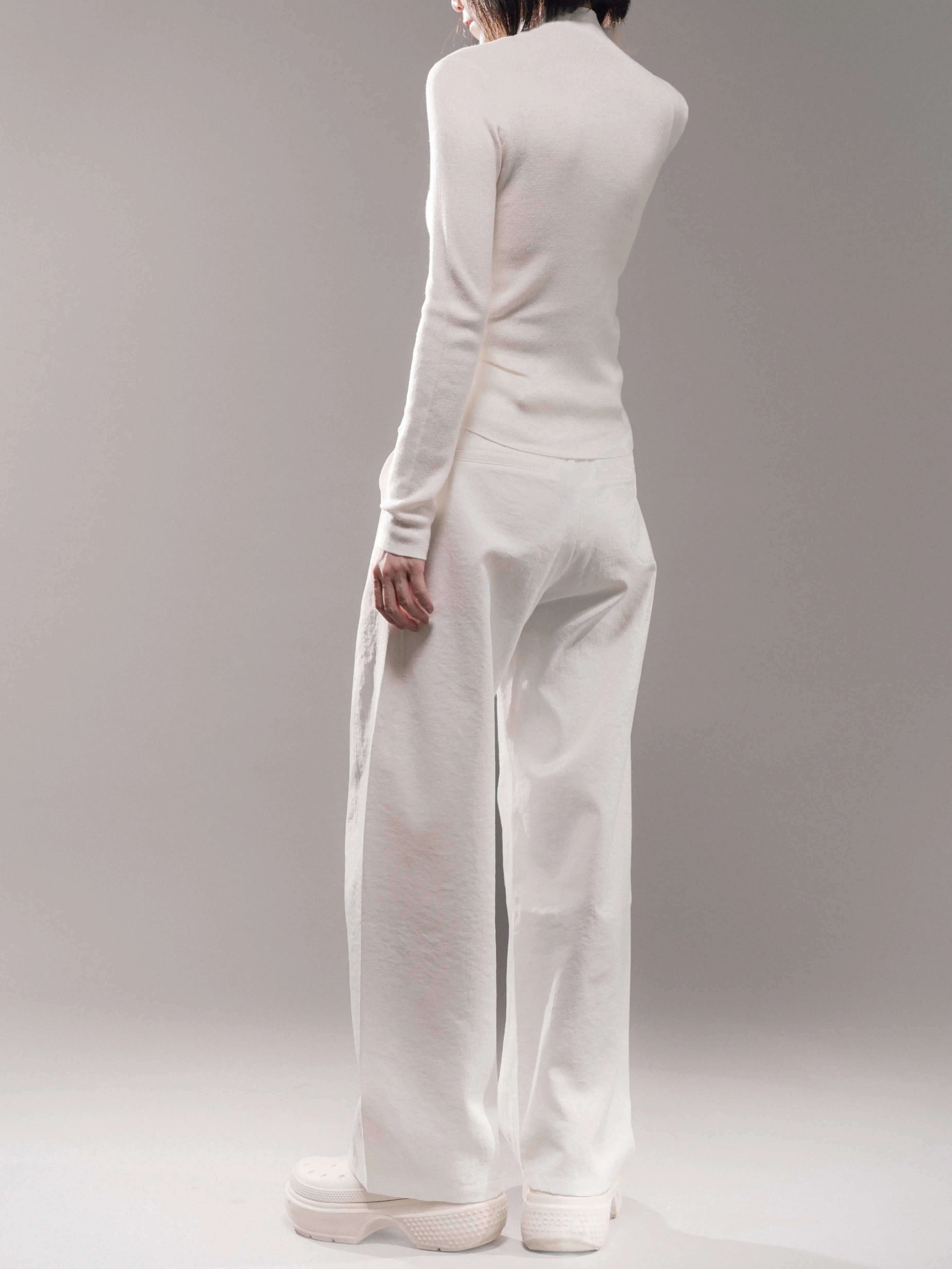 Back-angle view of white Japanese hollow yarn trousers, smooth waistband, structured cocoon shape, breathable texture.