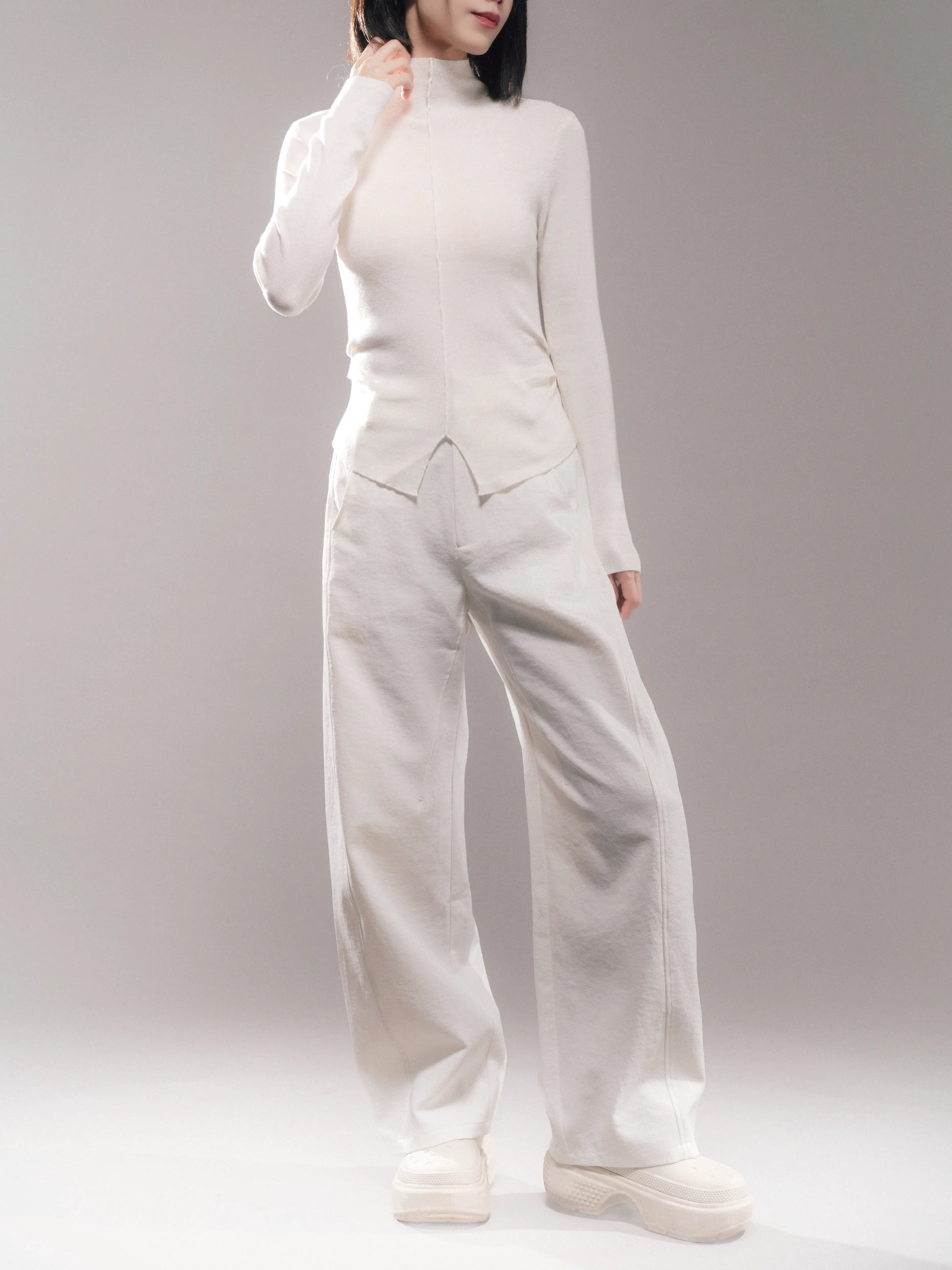 Front full-body view of white hollow yarn cocoon trousers, lightweight fall, relaxed drape, paired with fitted white knit top.
