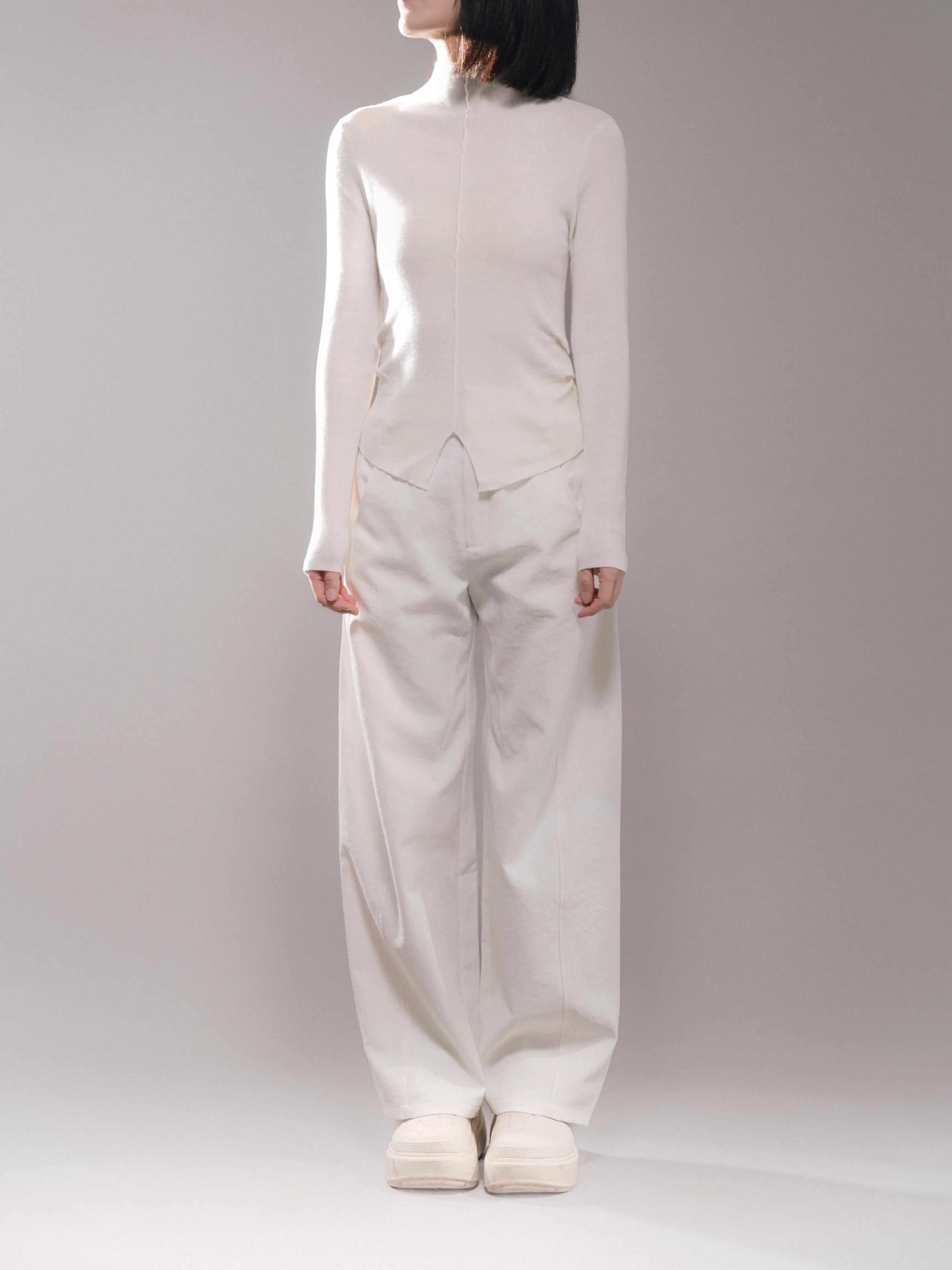 White cocoon trousers styled in a clean all-white outfit, minimal composition, soft leg volume, modern proportion.