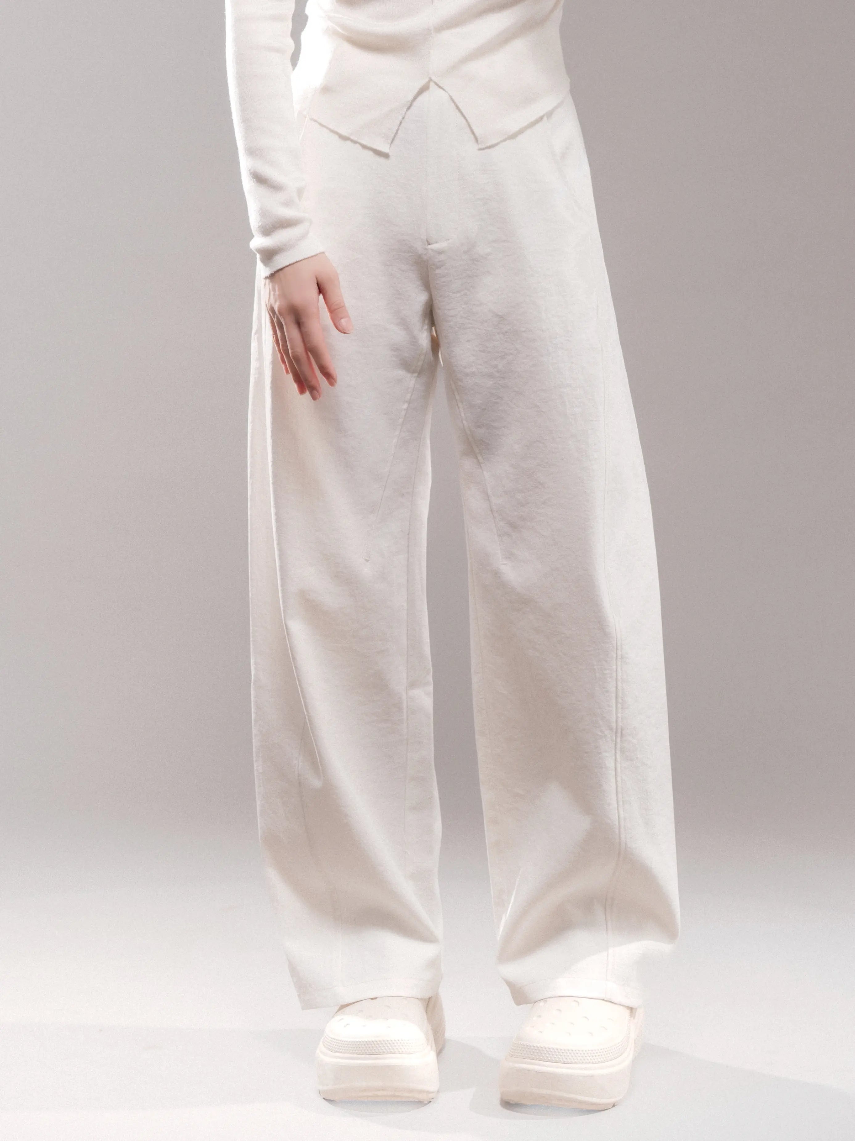 Model wearing white Japanese hollow yarn cocoon trousers, soft matte texture, wide-leg silhouette, minimal styling, clean white studio background.