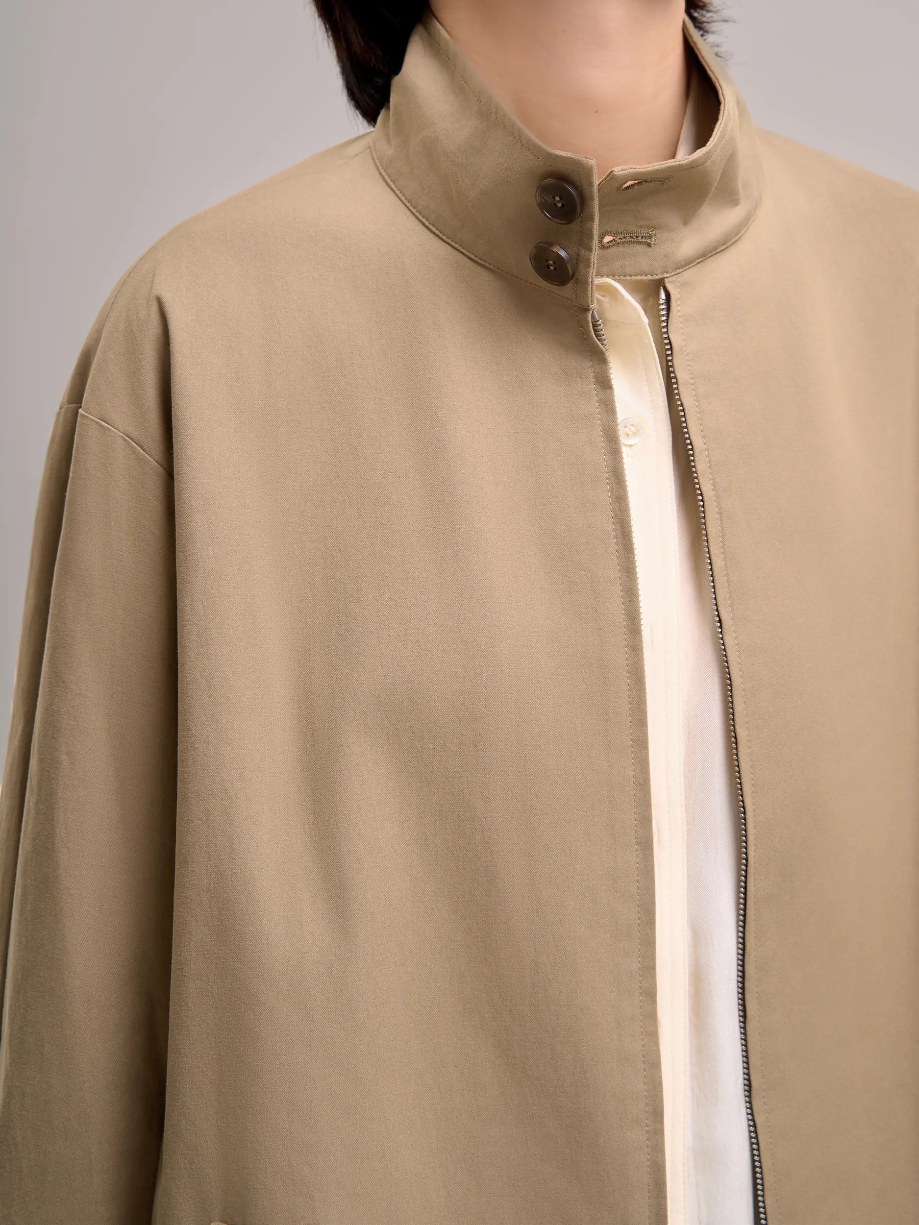 Close-up of khaki trench coat collar detail, highlighting clean tailoring and refined minimalist craftsmanship.