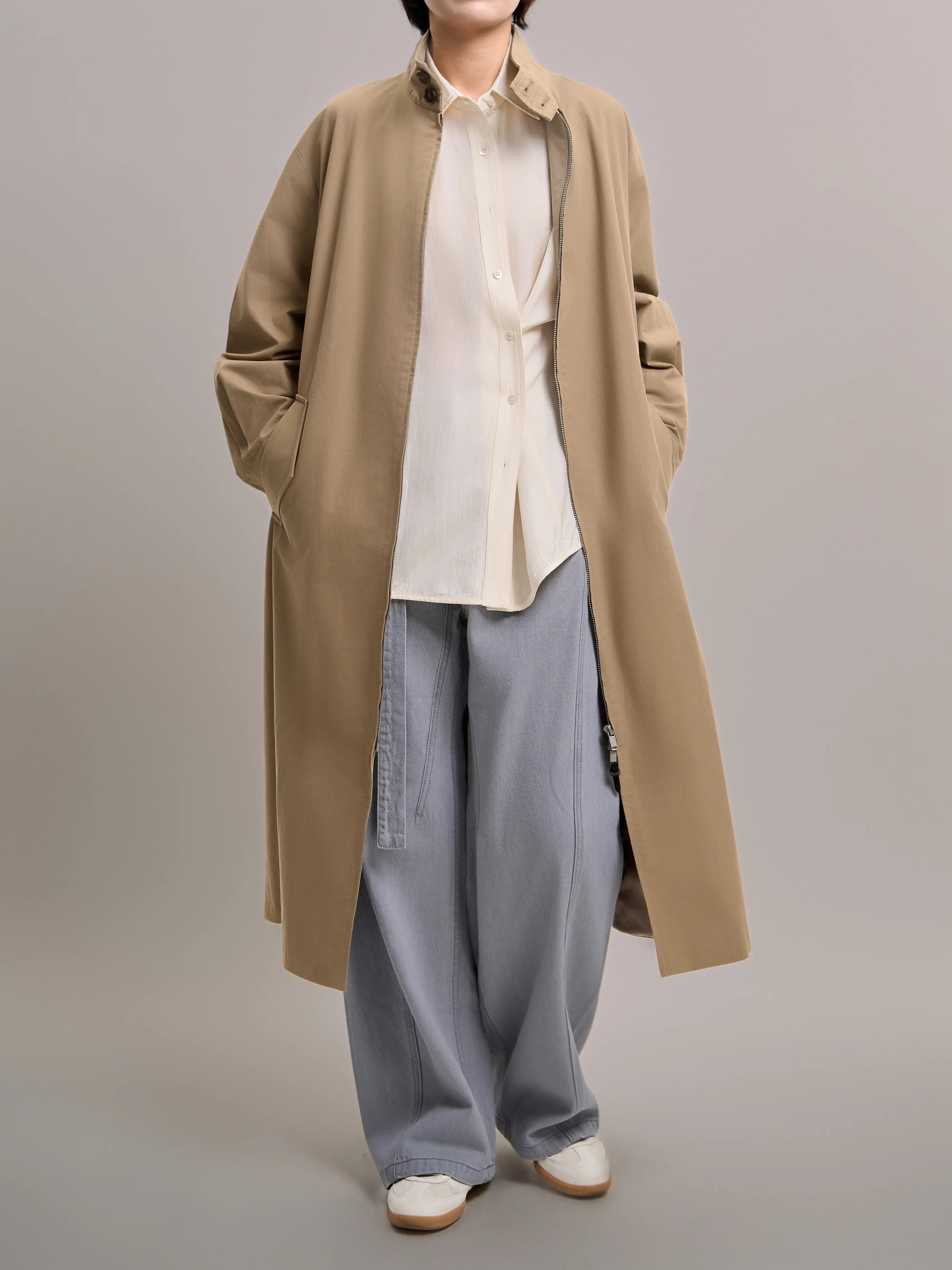 Front view of khaki trench coat styled with wide-leg trousers, showcasing a clean minimalist full-body city outfit.