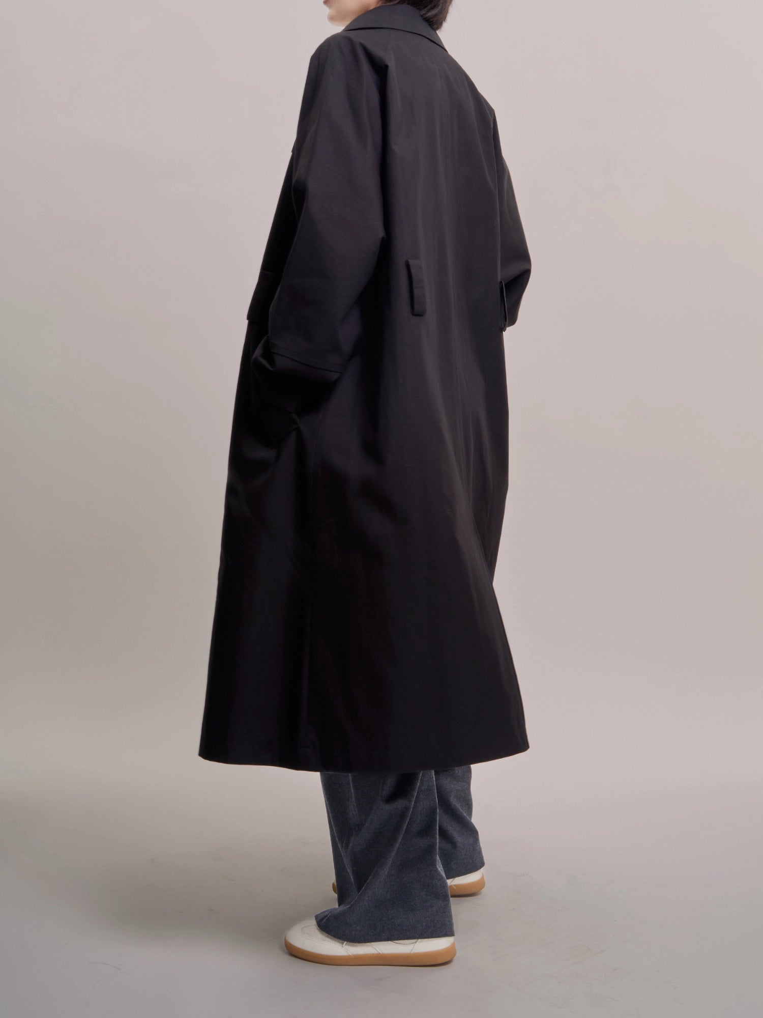 Back view of black Noir Trench showing minimal seams and soft structured volume.