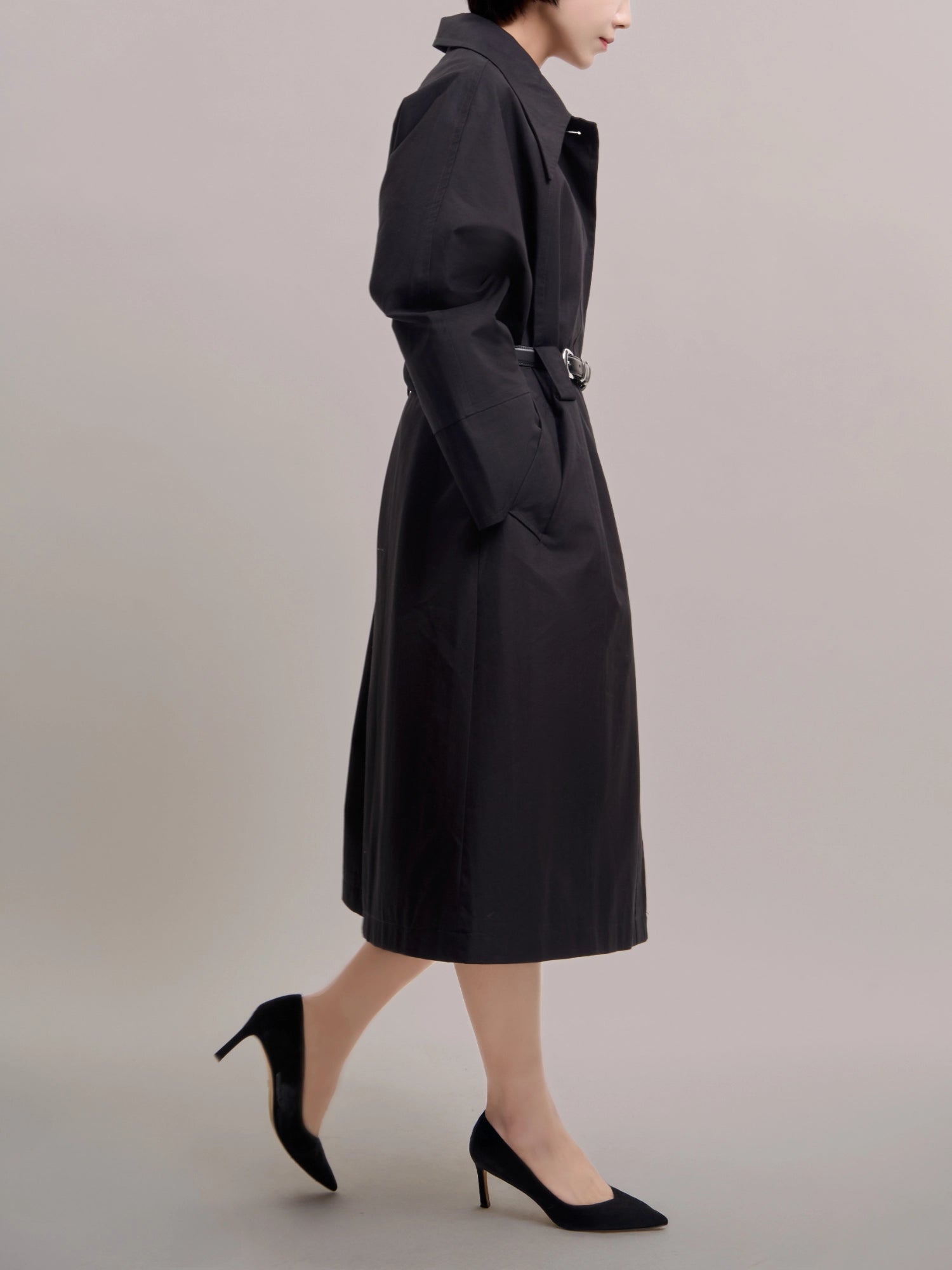 Side mid-length view of Noir Trench with belt, showcasing clean waist definition.