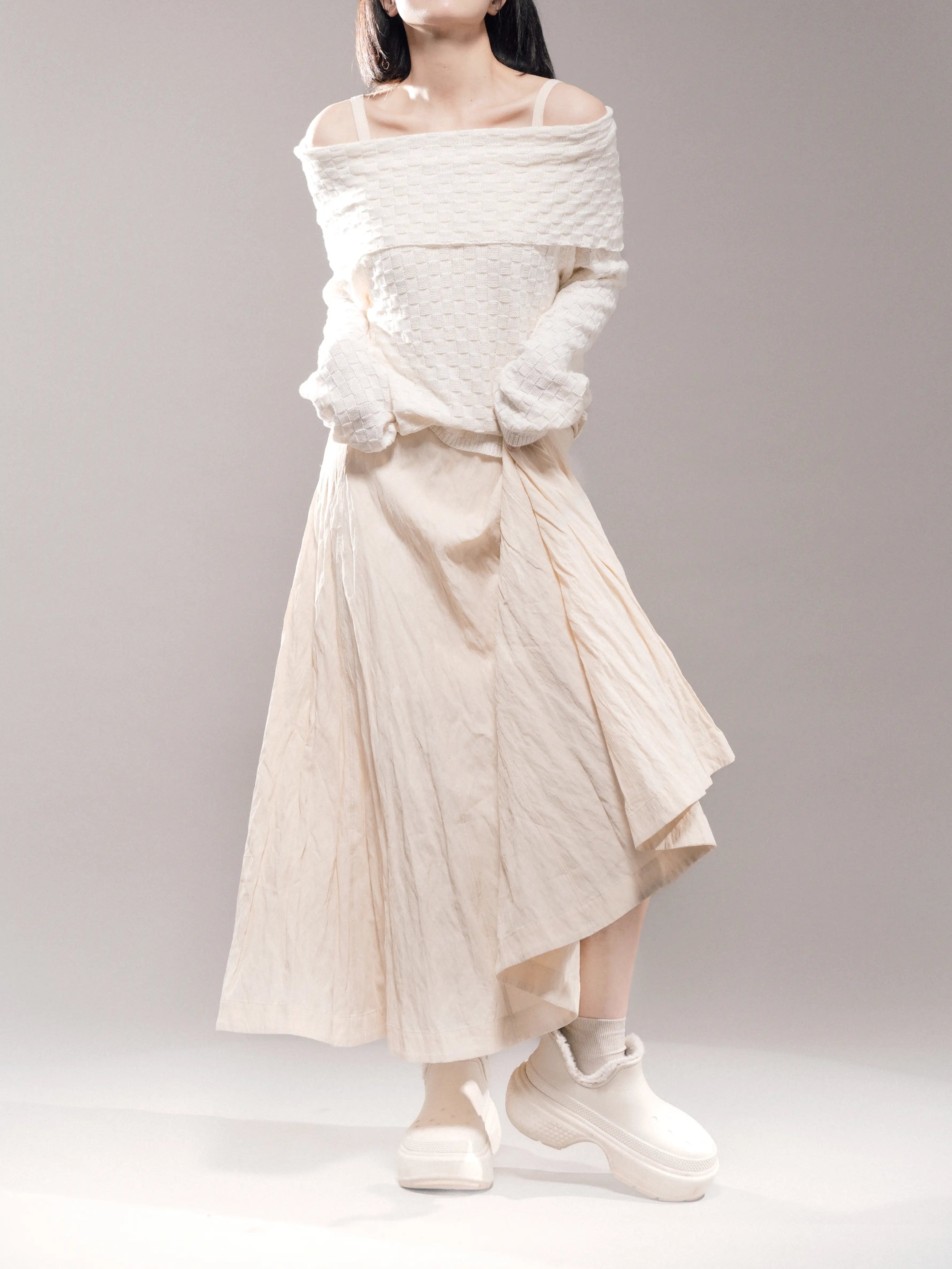 White off-shoulder sweater styled with full ivory skirt, soft movement shot, lightweight knit for daily layering outfits.

