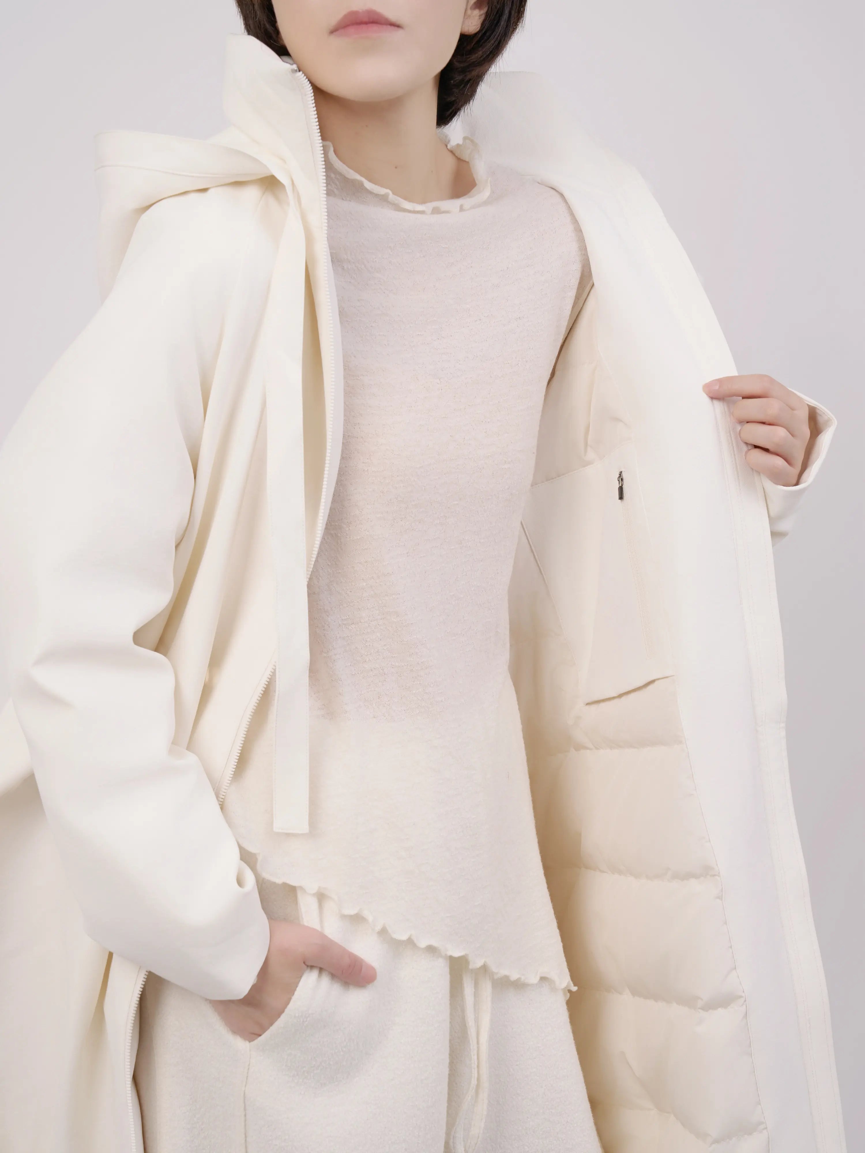 Inner detail of off-white hooded down coat showing soft lining and layered structure.