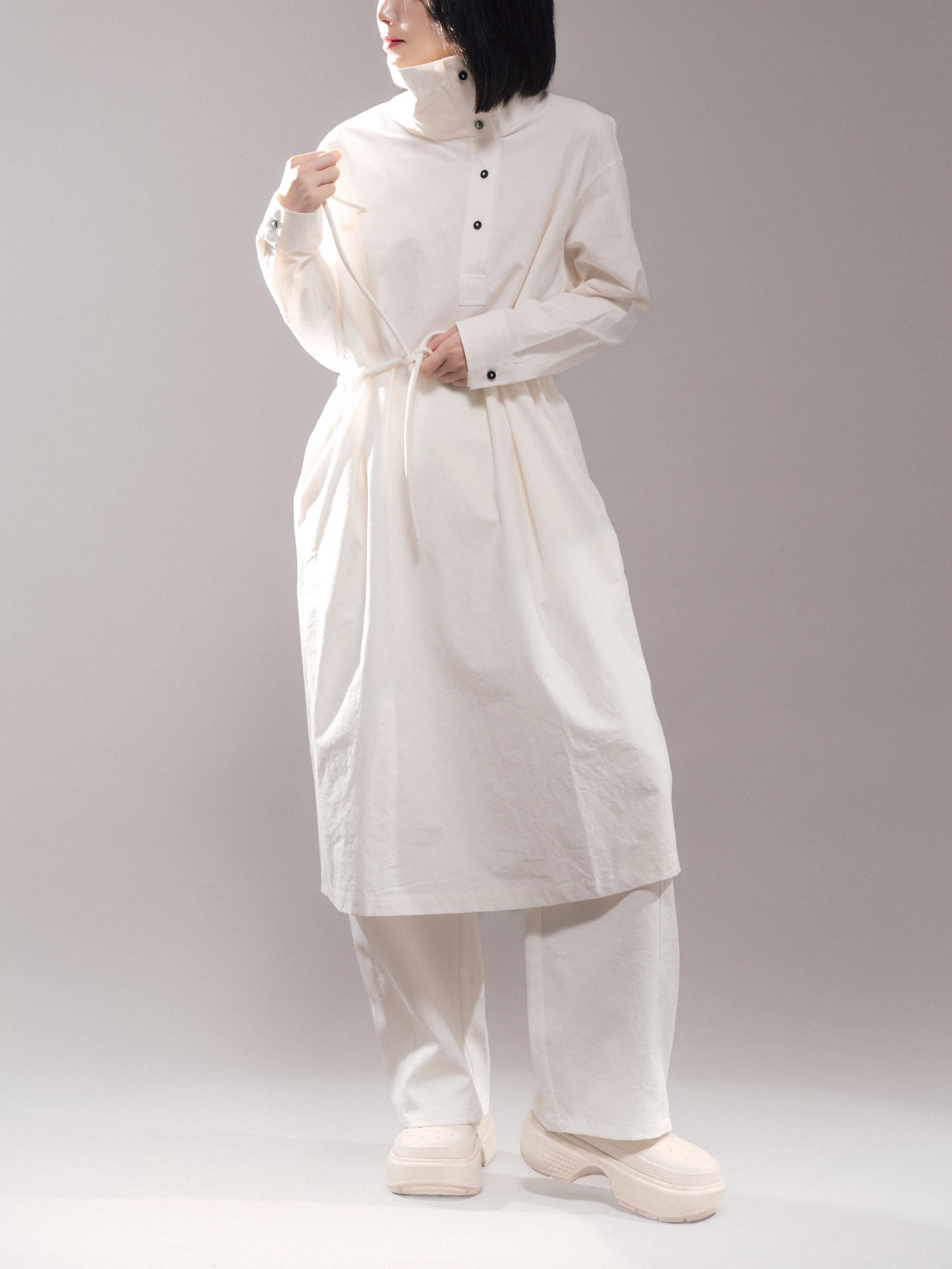 Front view of white Pima cotton stand-collar dress with rope-tied waist, breathable texture, soft structure.