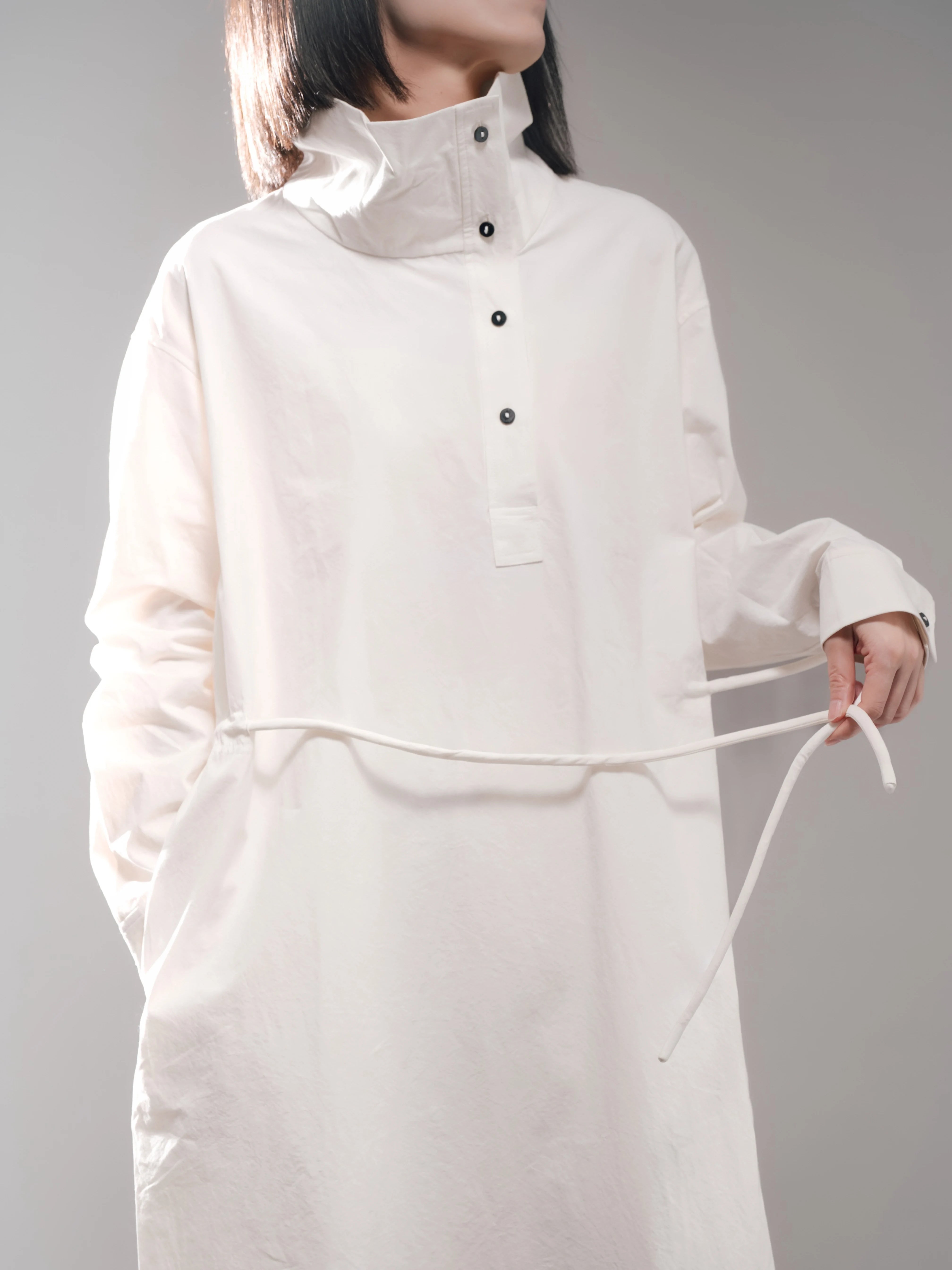 Close-up mid-length shot showcasing stand collar, button placket and cotton rope belt on Pima cotton dress.