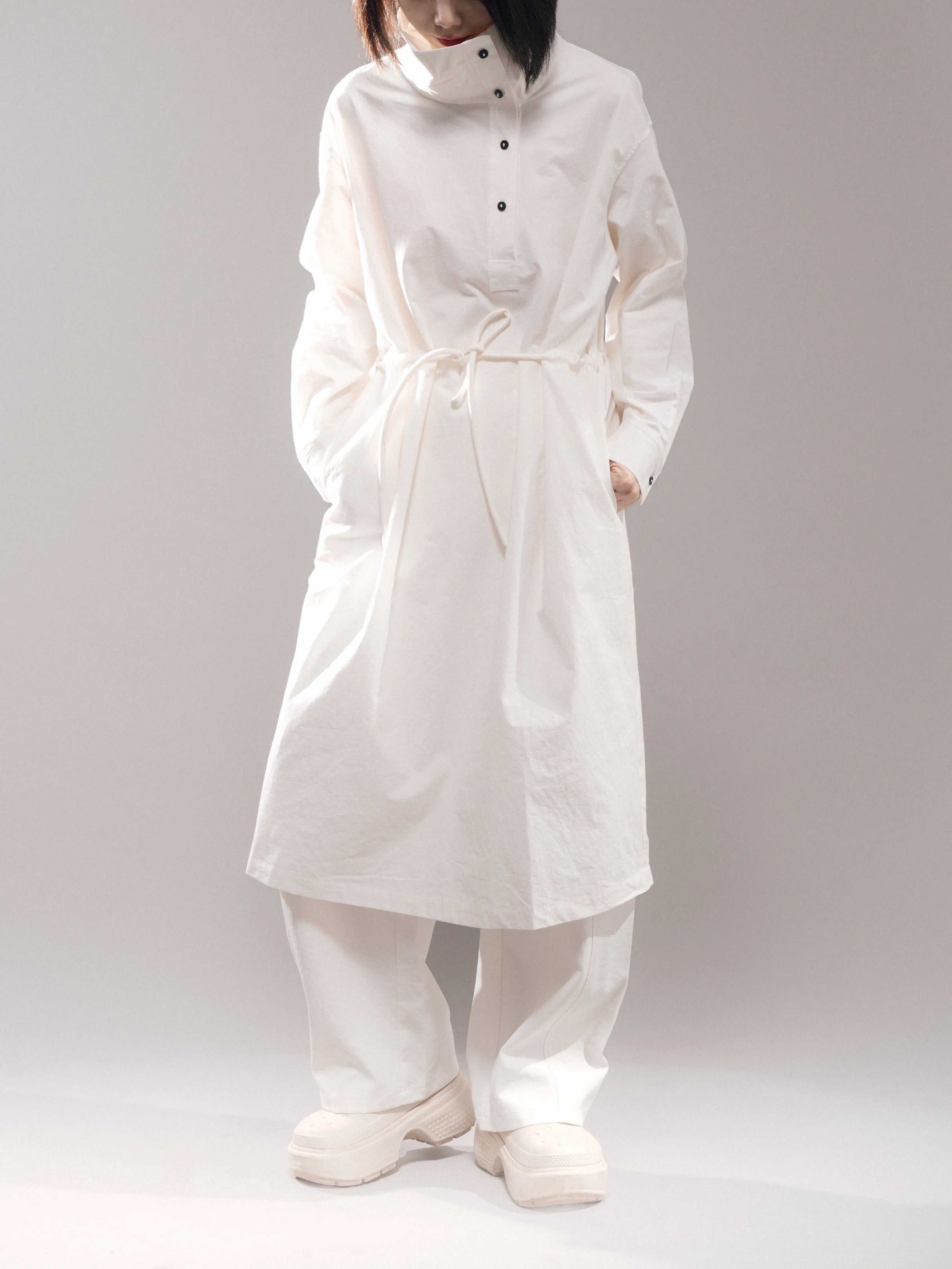 Full body view of white Pima cotton dress with stand collar and rope belt, styled with relaxed wide pants, minimalist aesthetic.