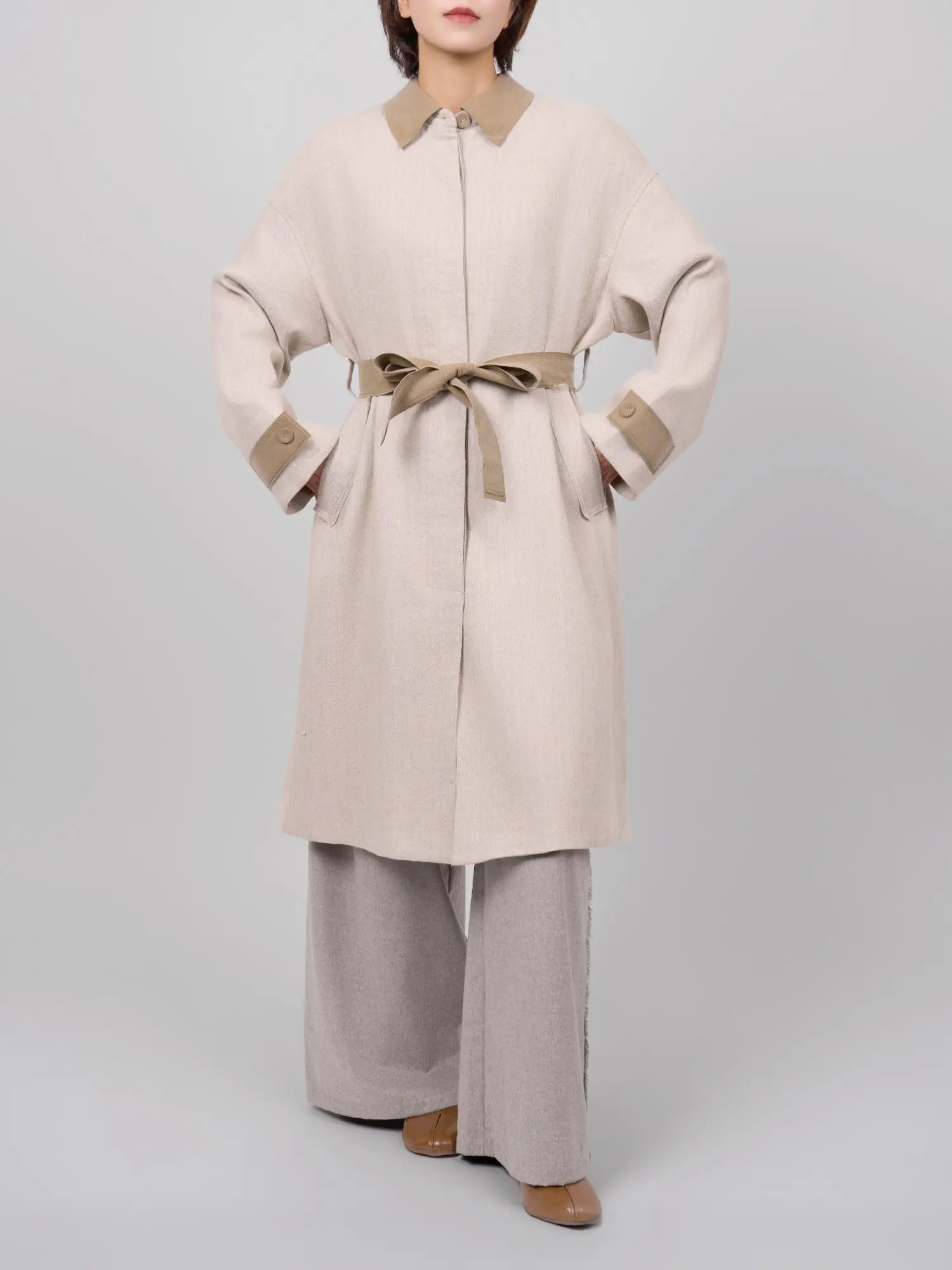 Belted look of the coat creating a defined waist and structured shape.