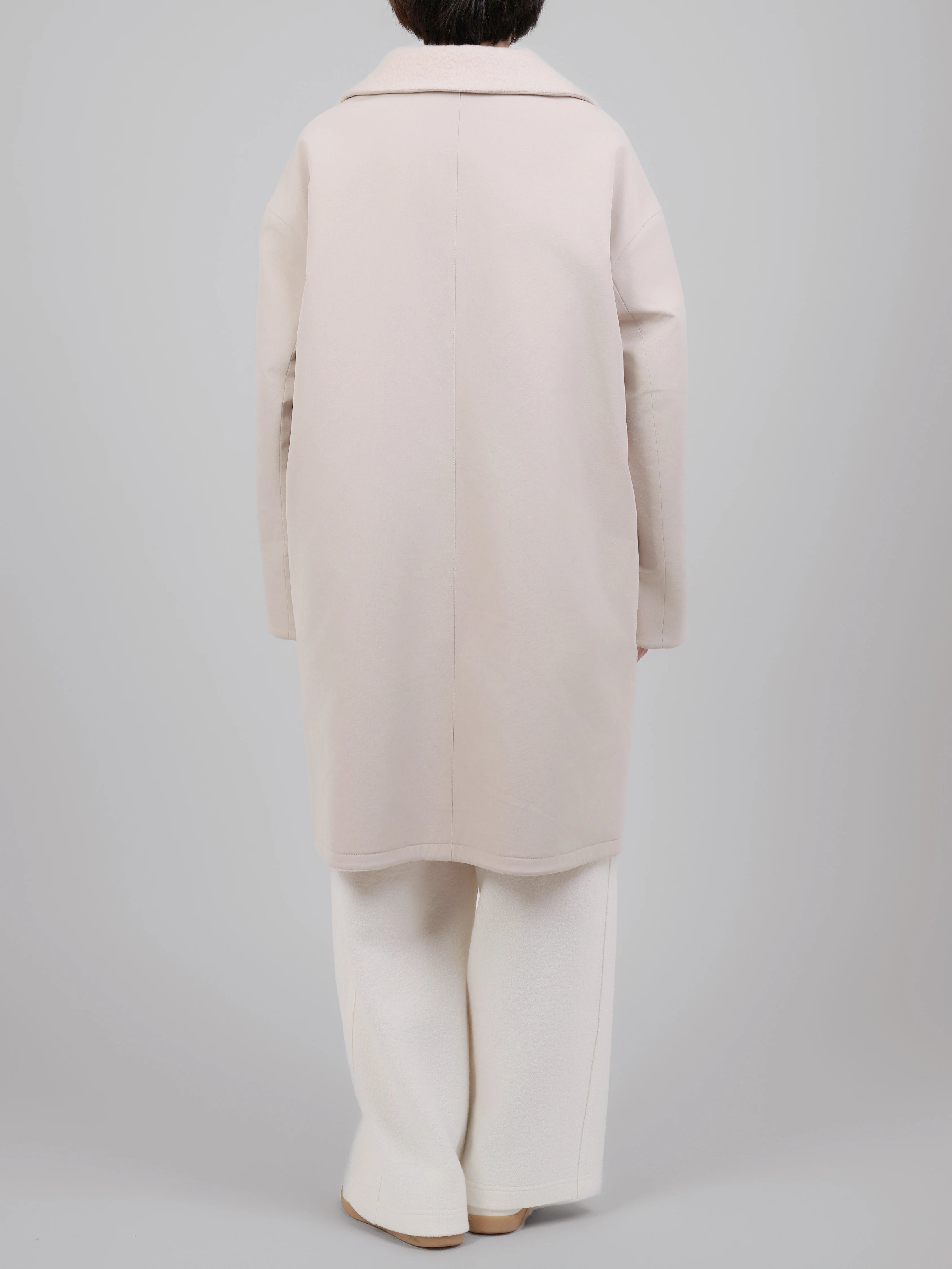 Back view of reversible wool coat with a clean, structured silhouette and minimal detailing.