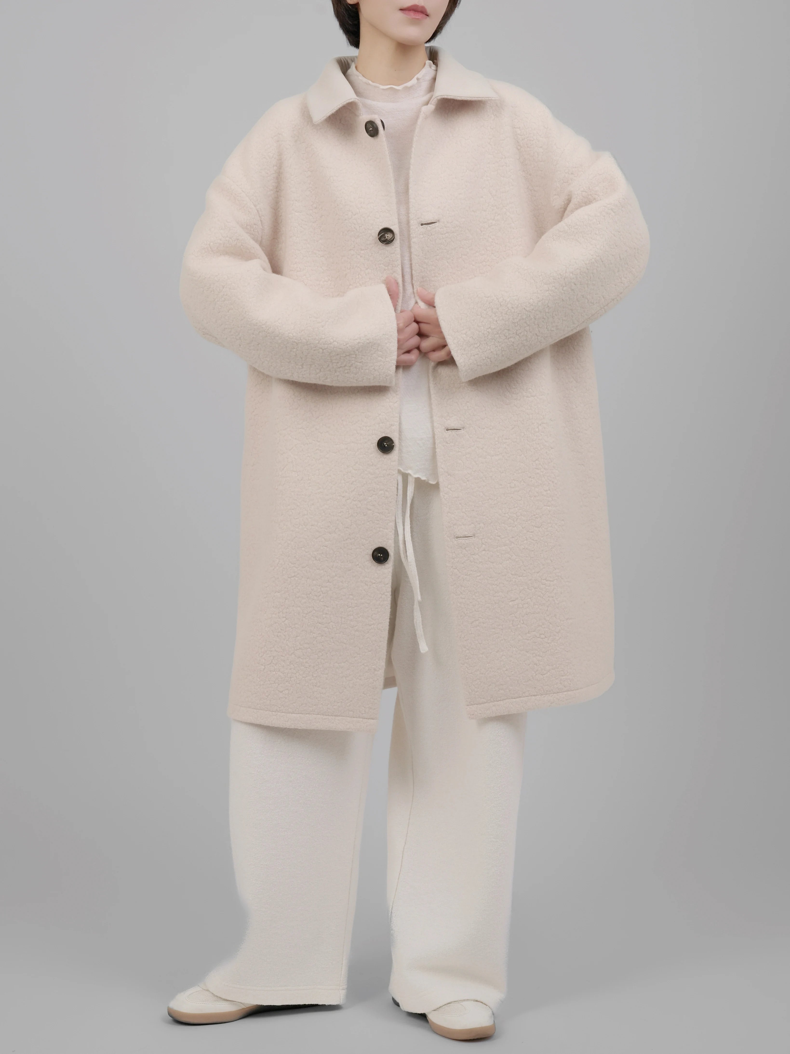 Front view of reversible wool coat in soft beige, featuring a clean straight cut and oversized fit.