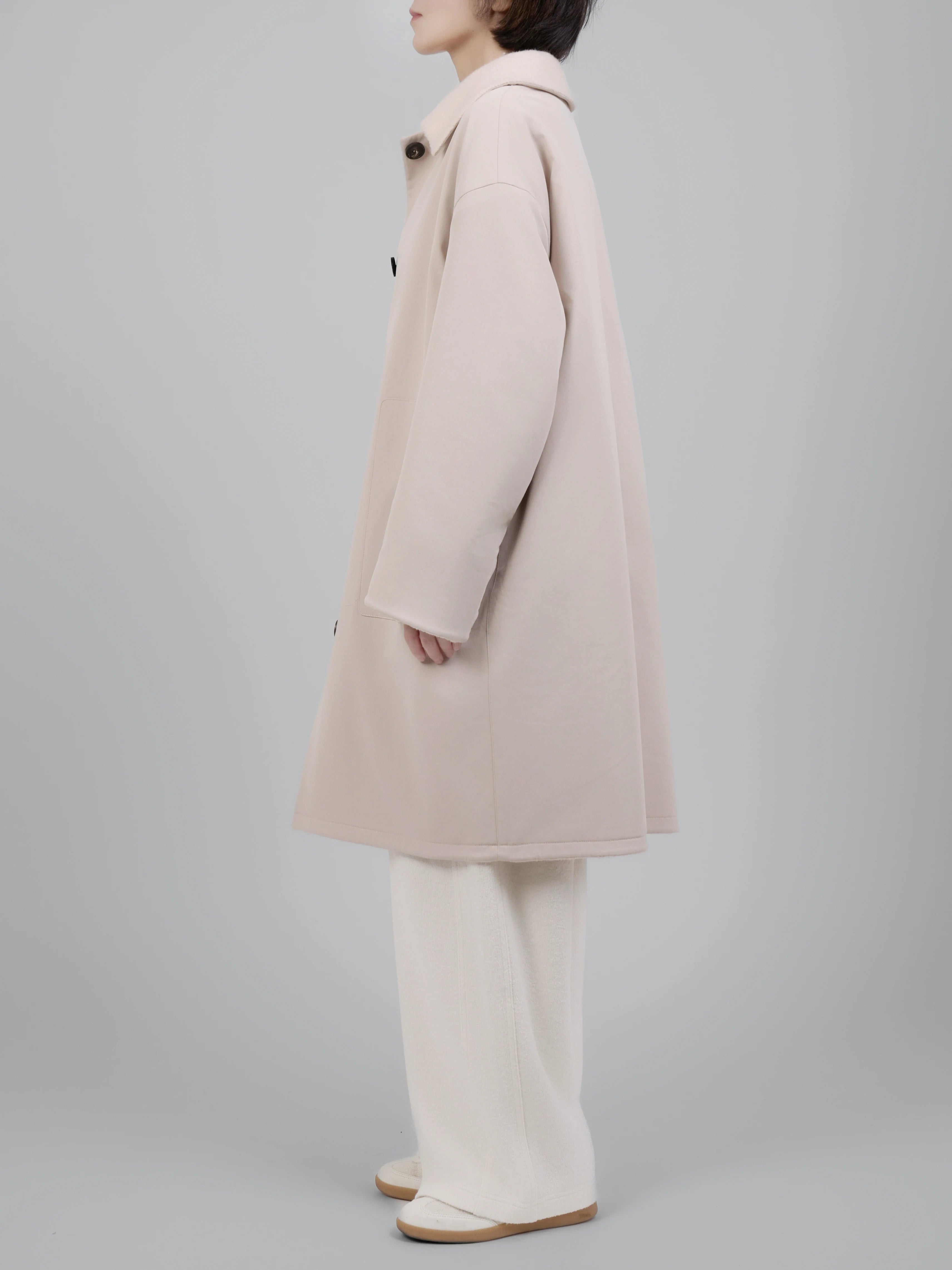 Side profile of long wool coat showing length, movement and layering potential.