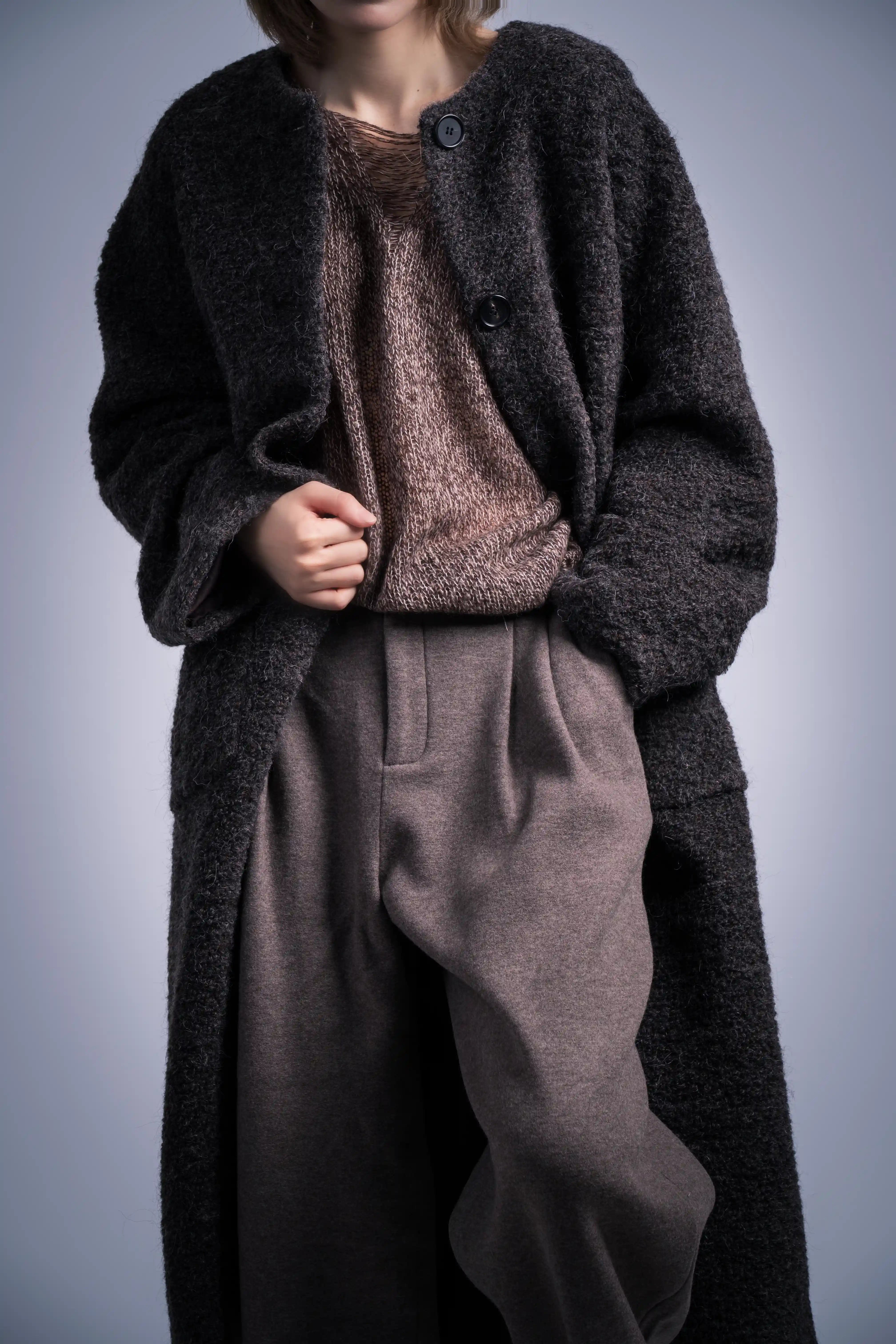 Model wearing charcoal coat styled with inner knit dress, soft winter layering, relaxed long silhouette.