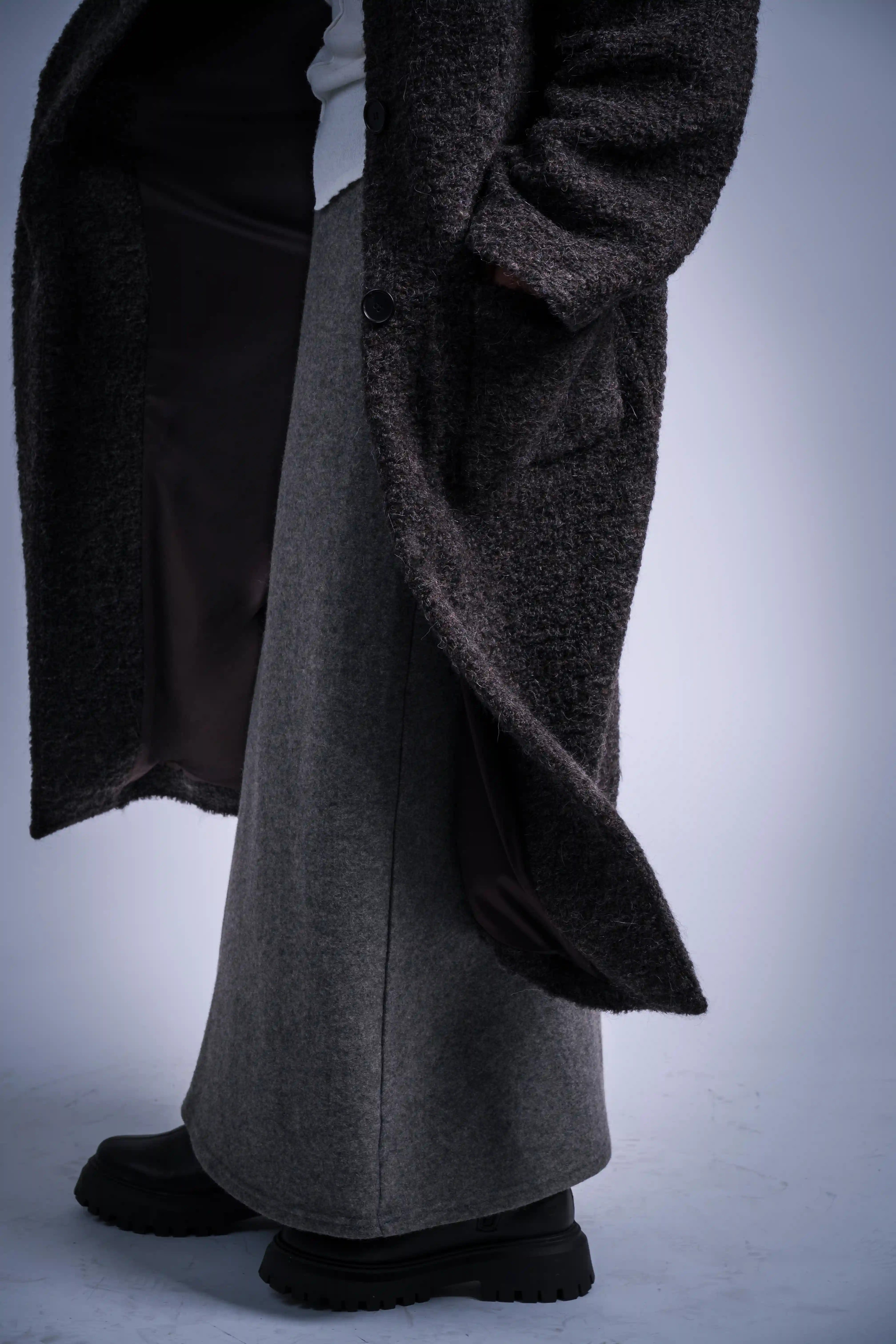 Close-up of coat hem and fabric texture, heavy drape, alpaca wool blend, refined winter tailoring.