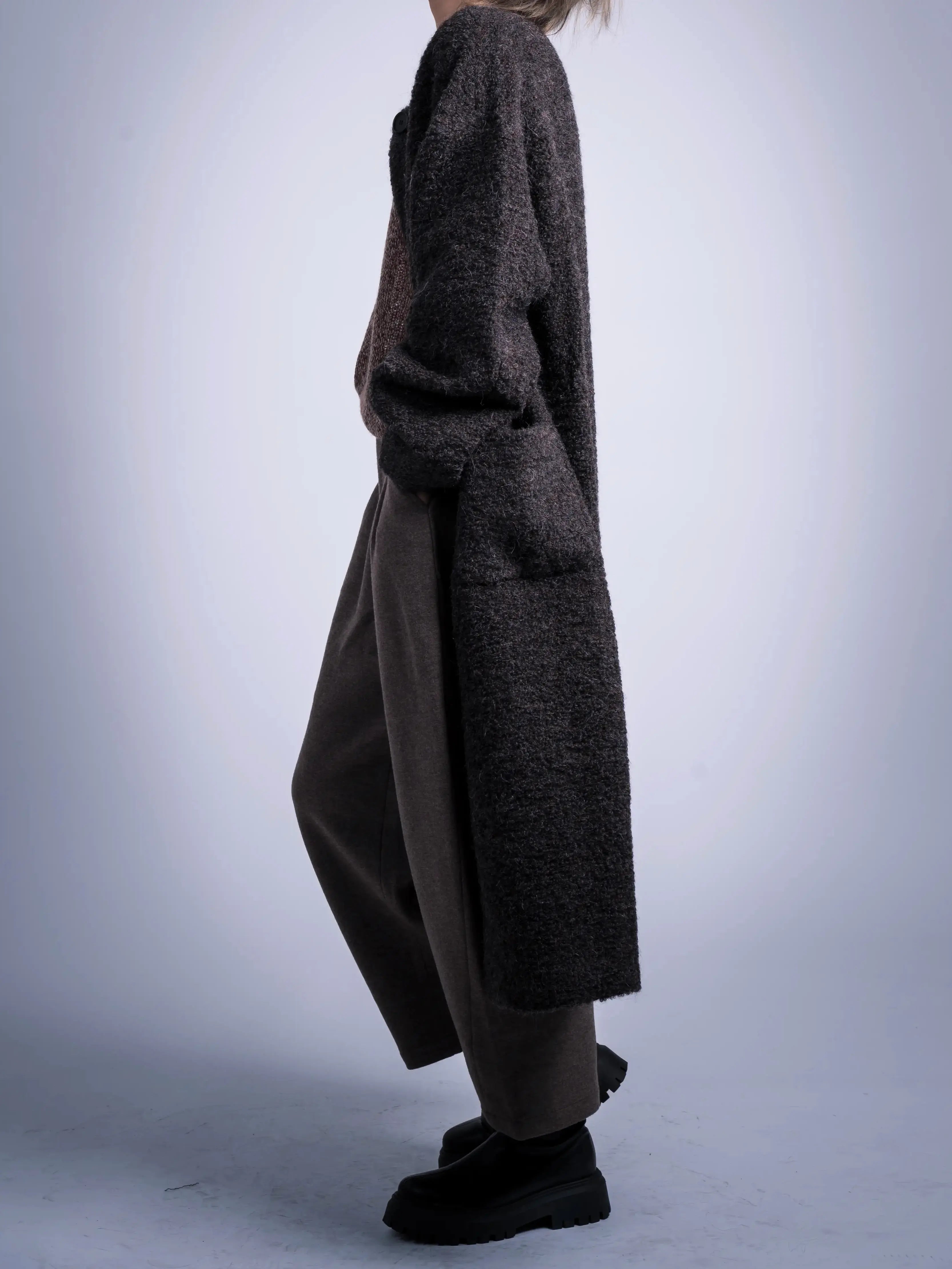 Model wearing charcoal alpaca-wool coat, full body side view, minimal winter styling, long relaxed silhouette, modern clean outerwear.