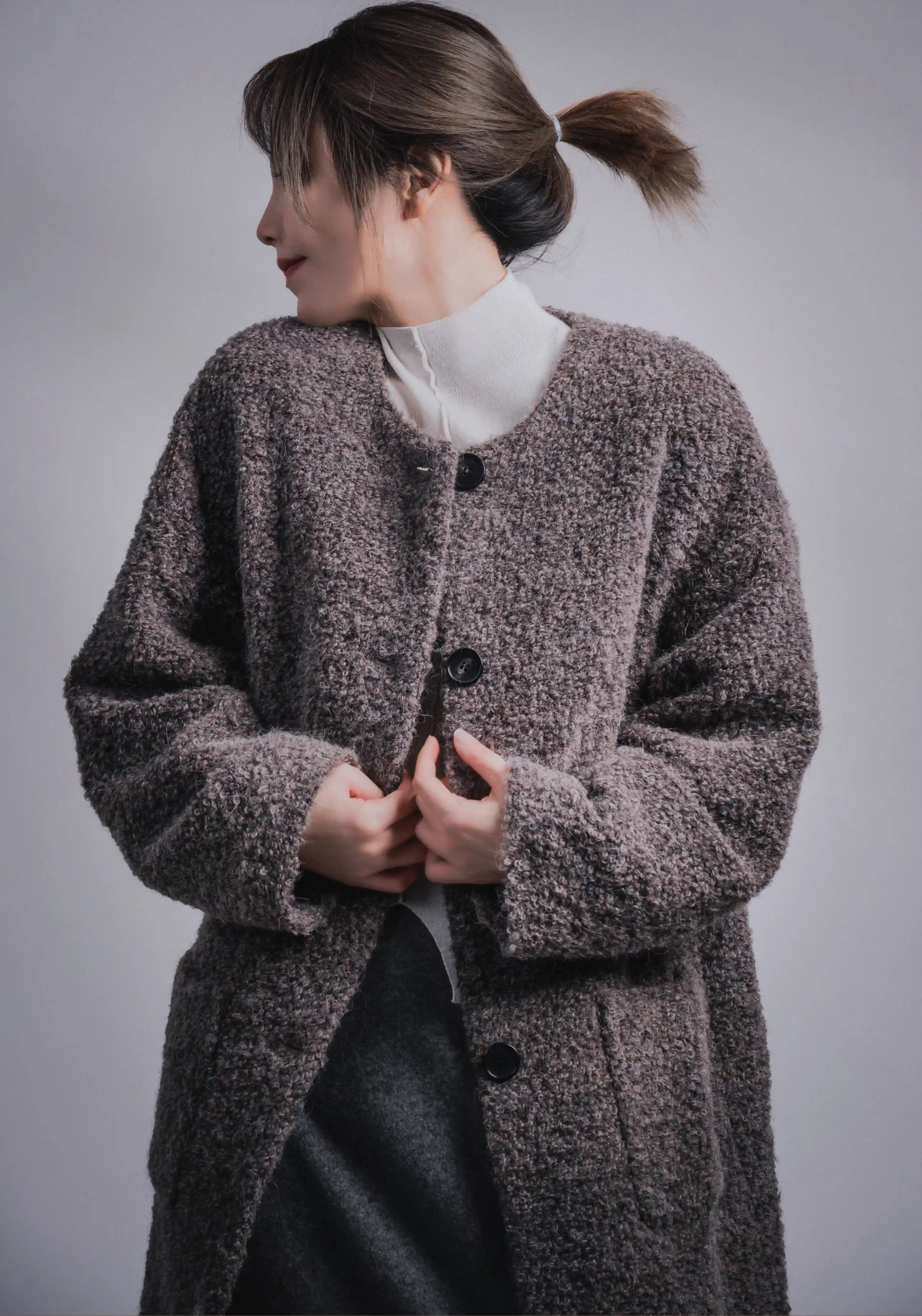 Close-up upper body view of grey wool coat, buttoned front, soft textured surface.