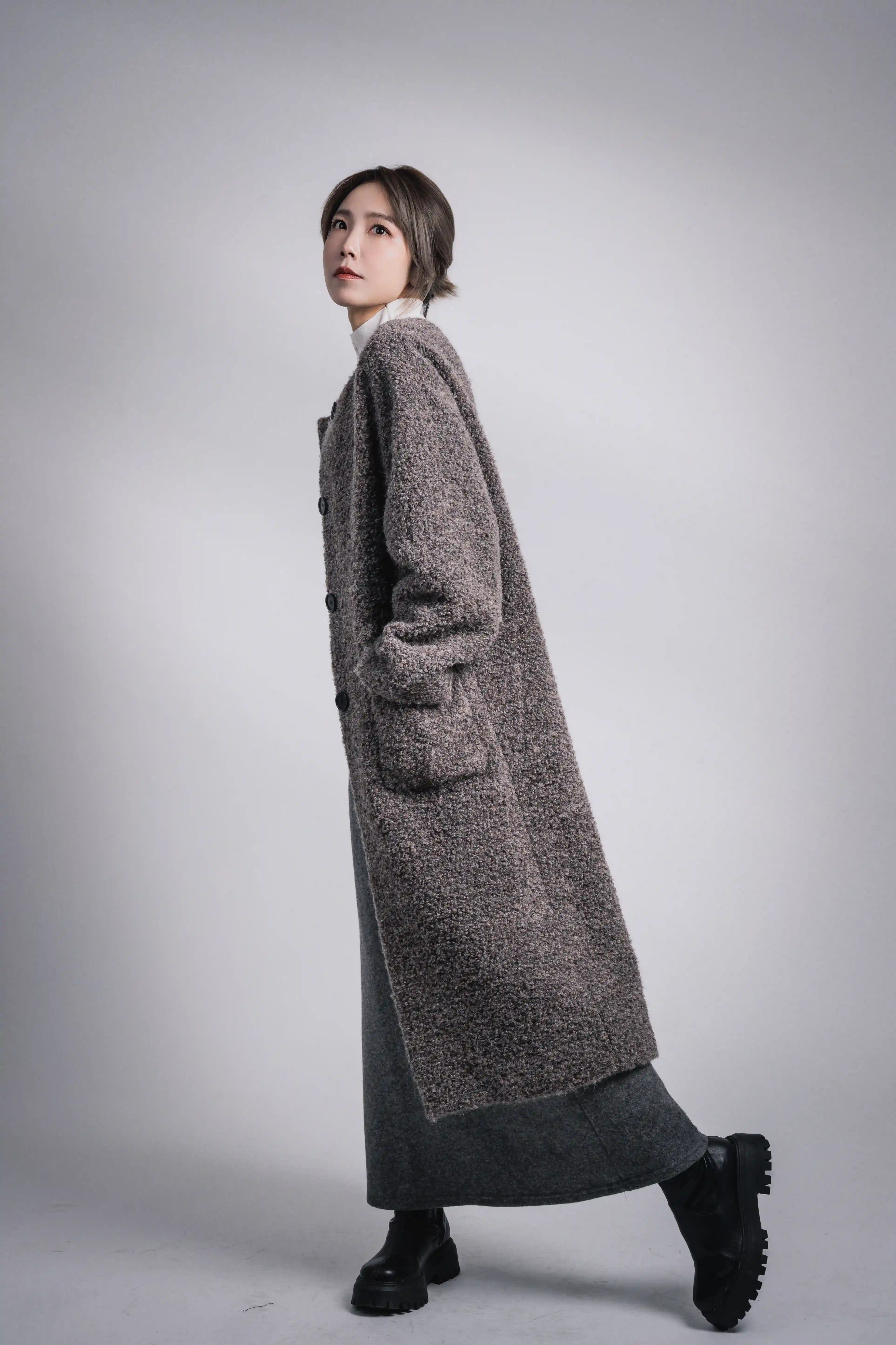 Model walking pose in grey alpaca wool coat, soft volume, minimal winter outerwear look.