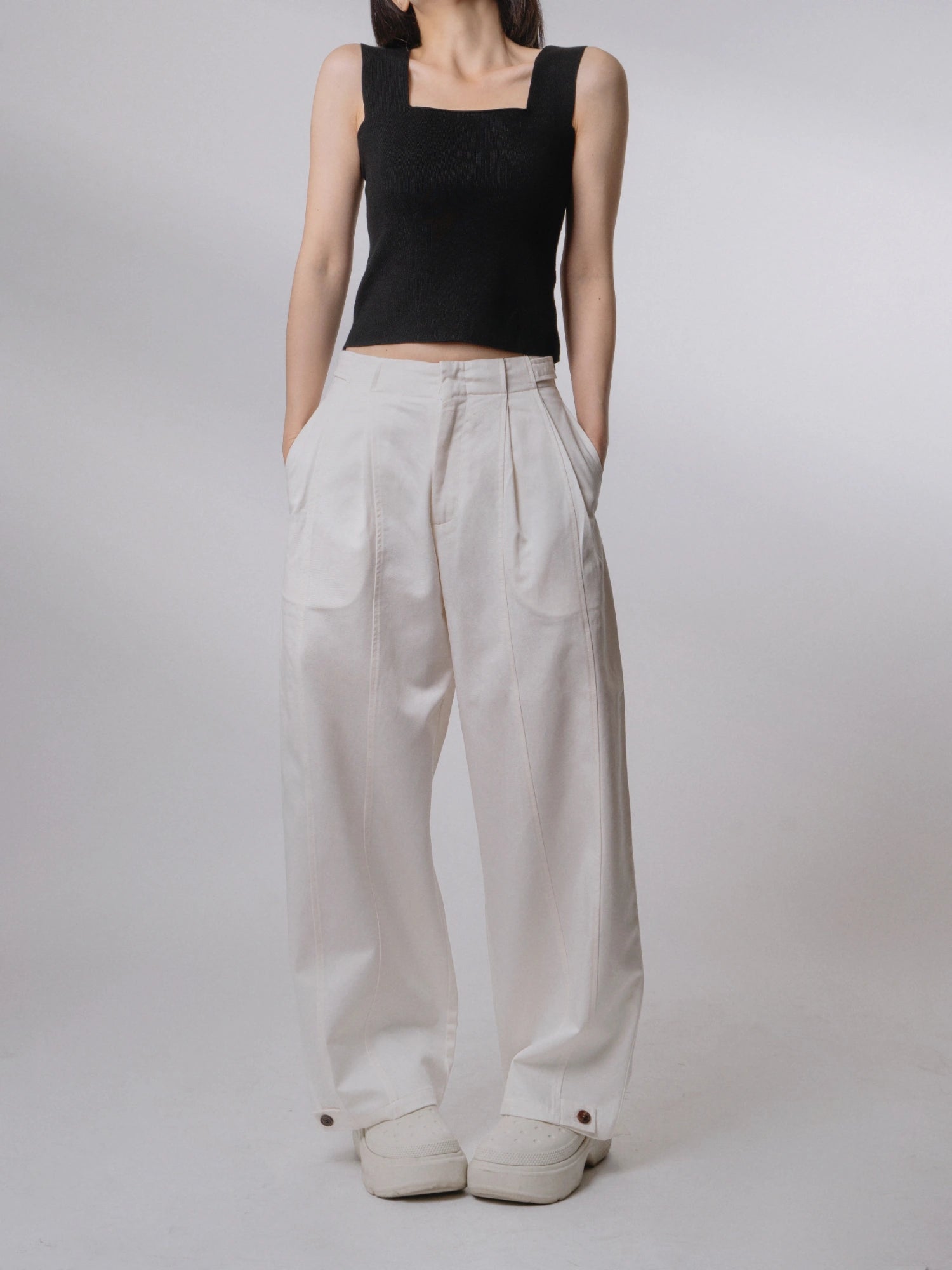 Model wearing white Tencel-cotton loose-fit trousers, high-waist wide-leg silhouette with soft drape, minimalist outfit front view.