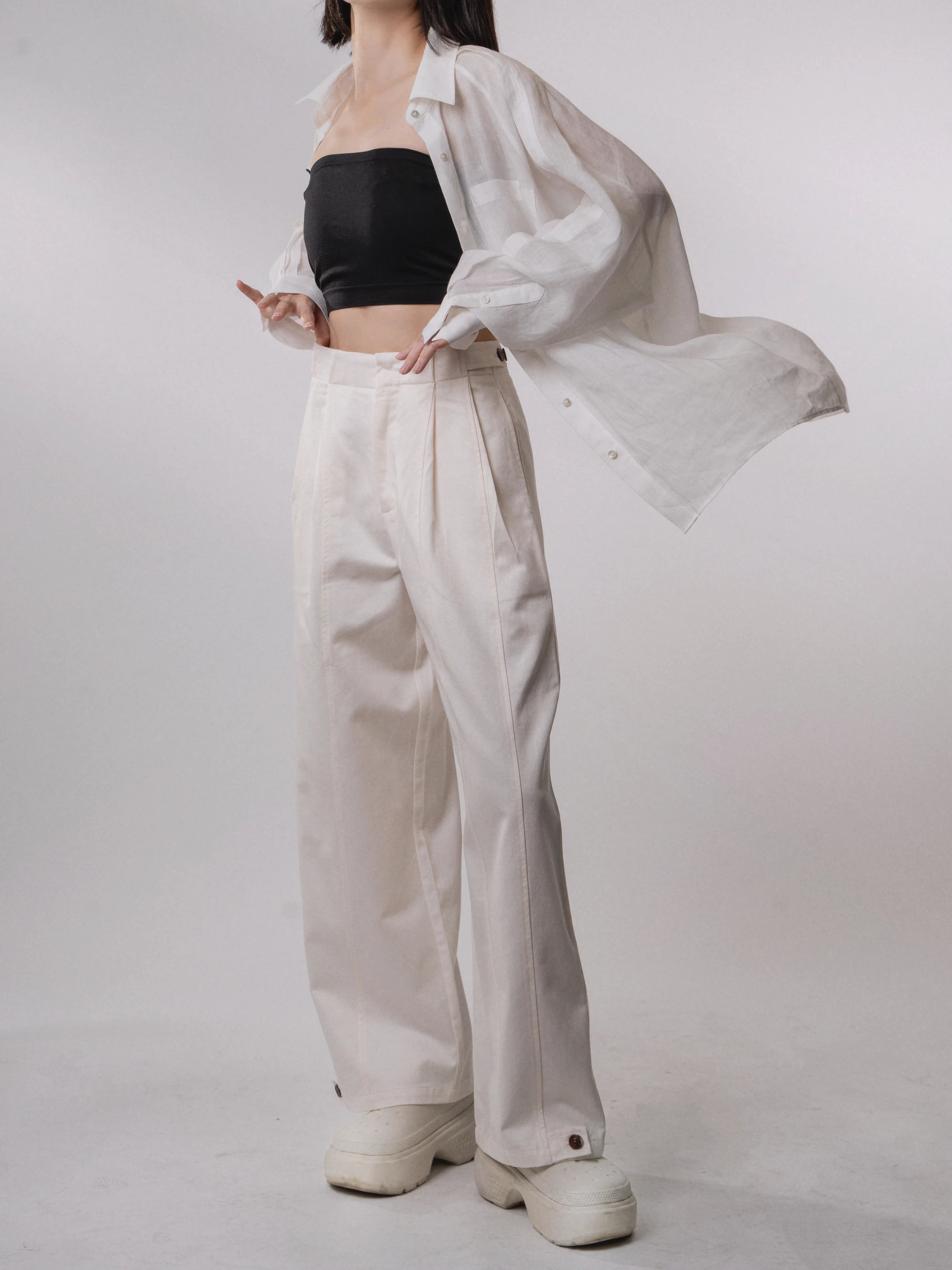 Side view of white Tencel-cotton loose trousers in motion, light flowing drape with relaxed fit, casual minimal styling.