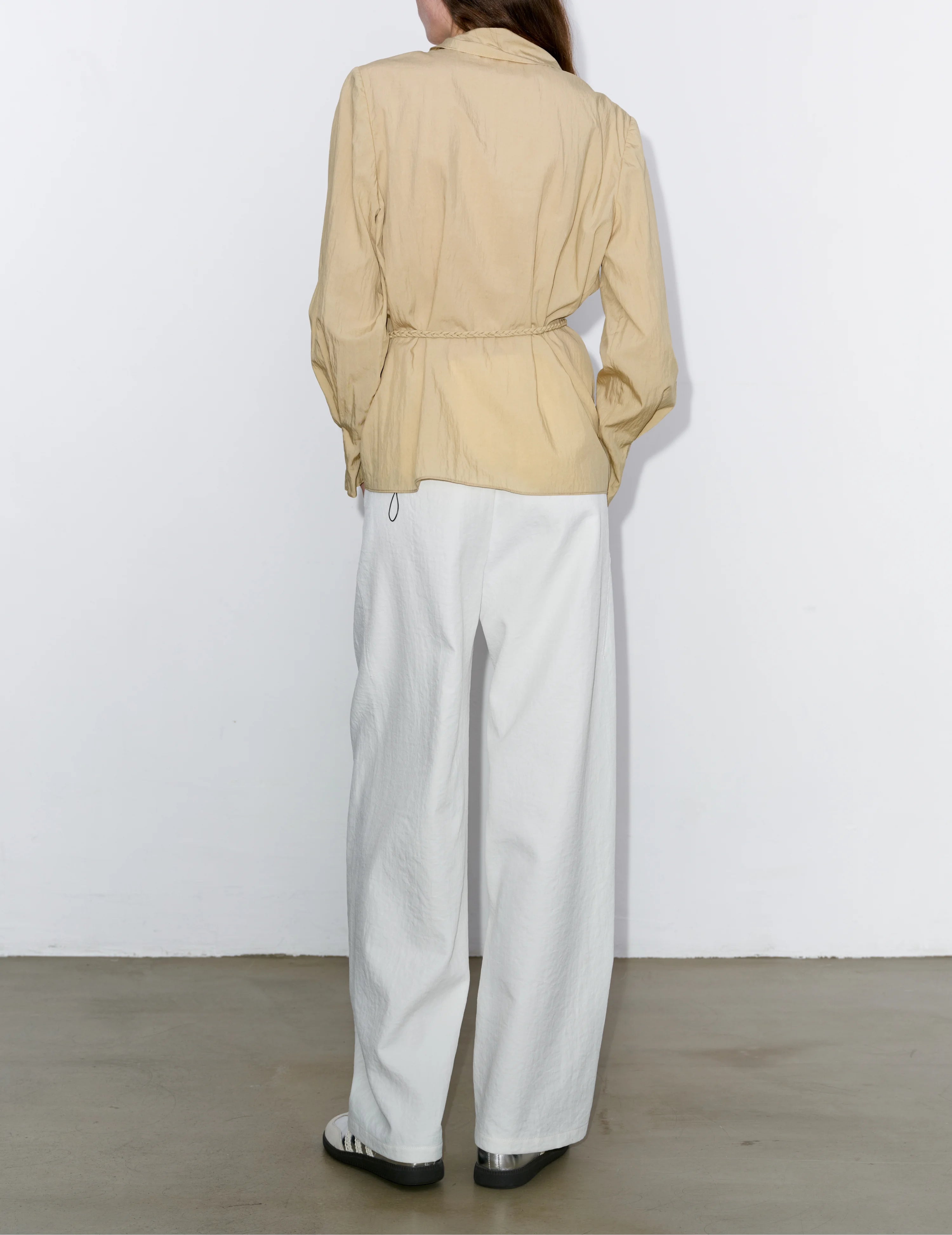 Back view of khaki Breeze Top, flowy silhouette, minimalist fit, lightweight fabric for warm-season layering, styled with white trousers.