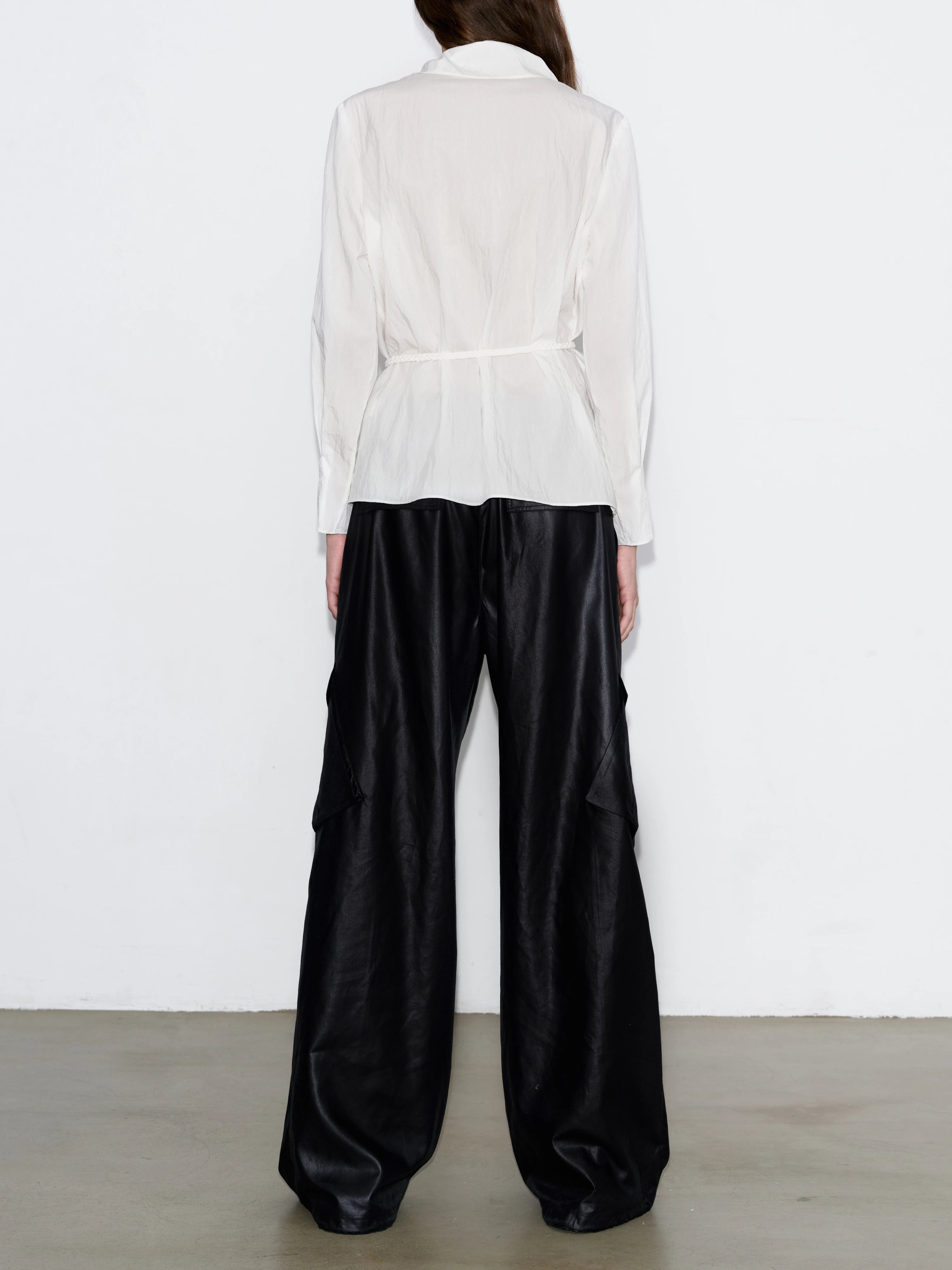 Back view of white Breeze Top with relaxed fit, flowy silhouette, clean minimal construction, paired with dark loose pants, casual styling.