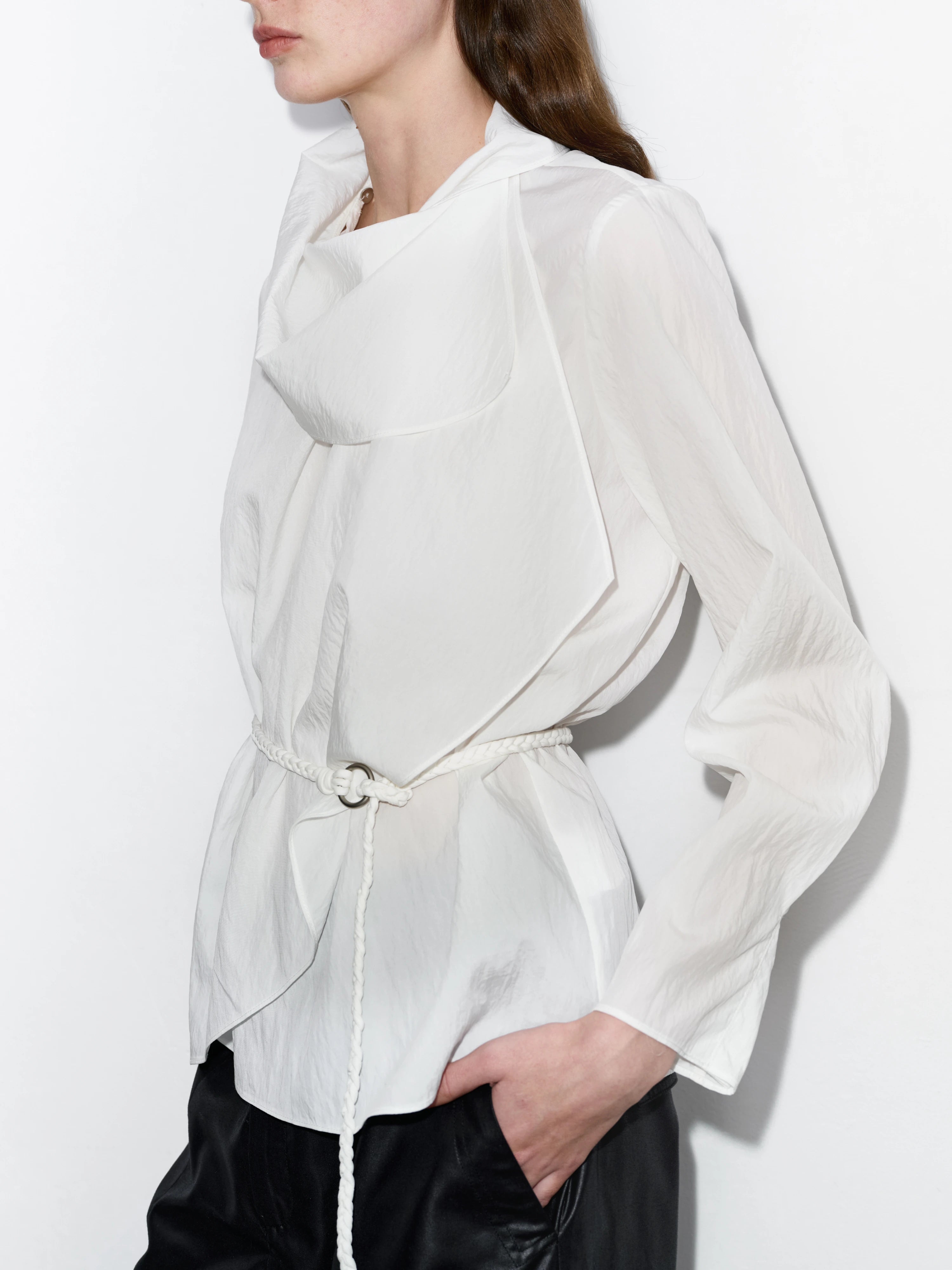 Side view of white Tencel-nylon Breeze Top, soft drape, adjustable rope waist, breathable fabric, styled with loose black trousers for everyday wear.