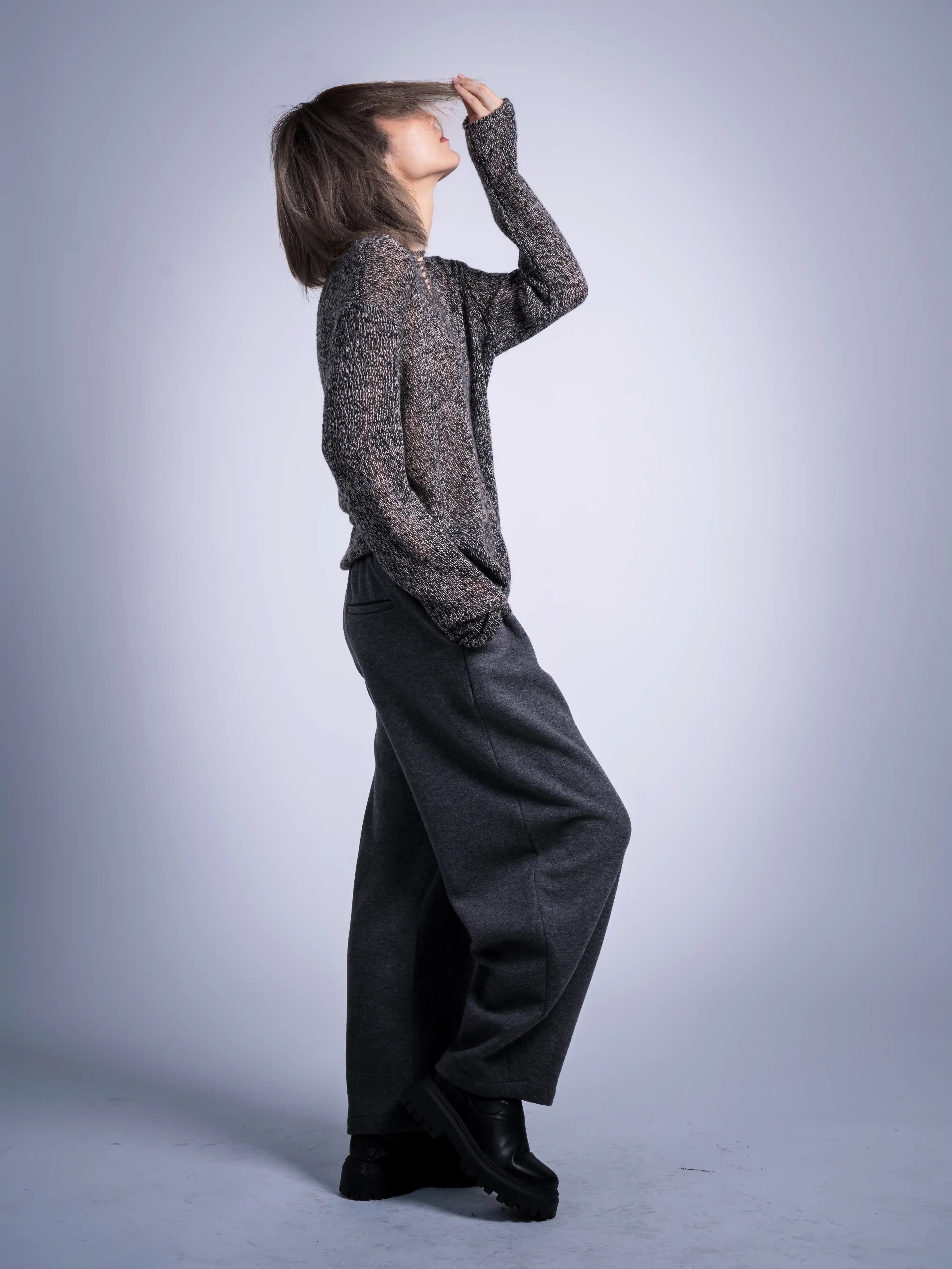 Side view of grey wool trousers, relaxed winter fit, styled with soft brown knit for casual layering.