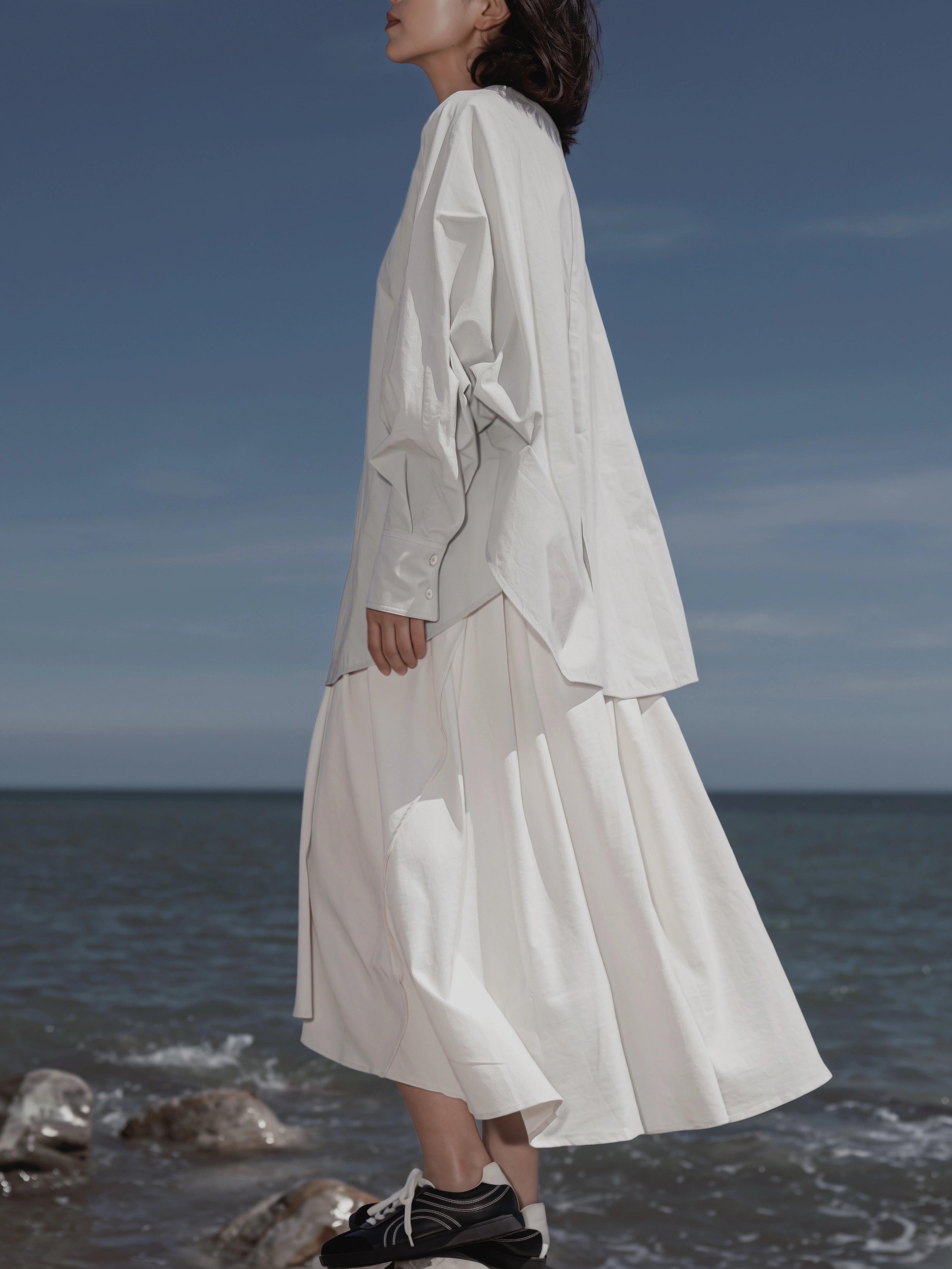 Side view of the Batwing Pullover in Sage at the beach.