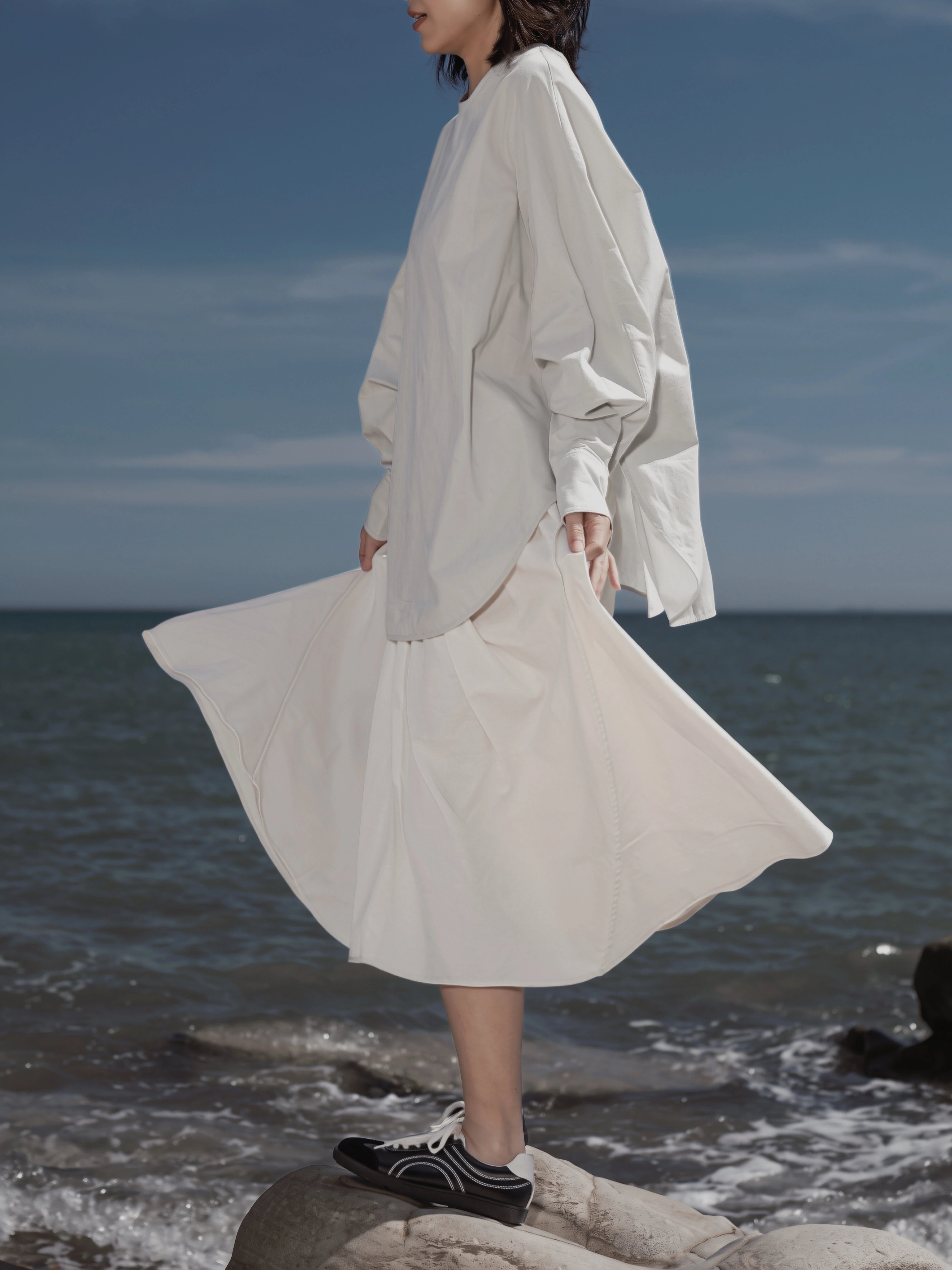 Batwing Pullover in Sage styled by the seaside, highlighting the fluid drape.