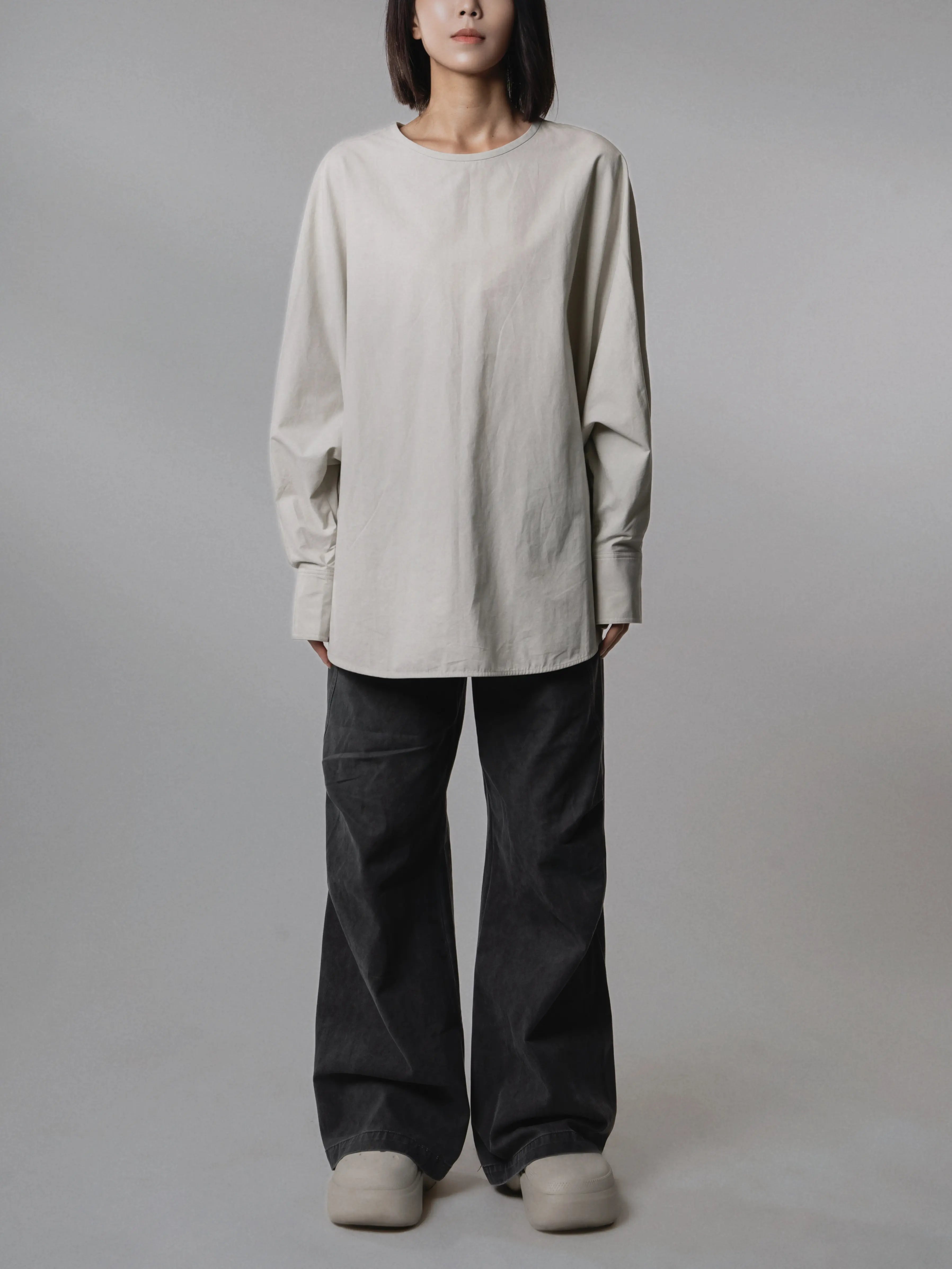 Front view of the Batwing Pullover in Muted Sage paired with relaxed wide-leg trousers.