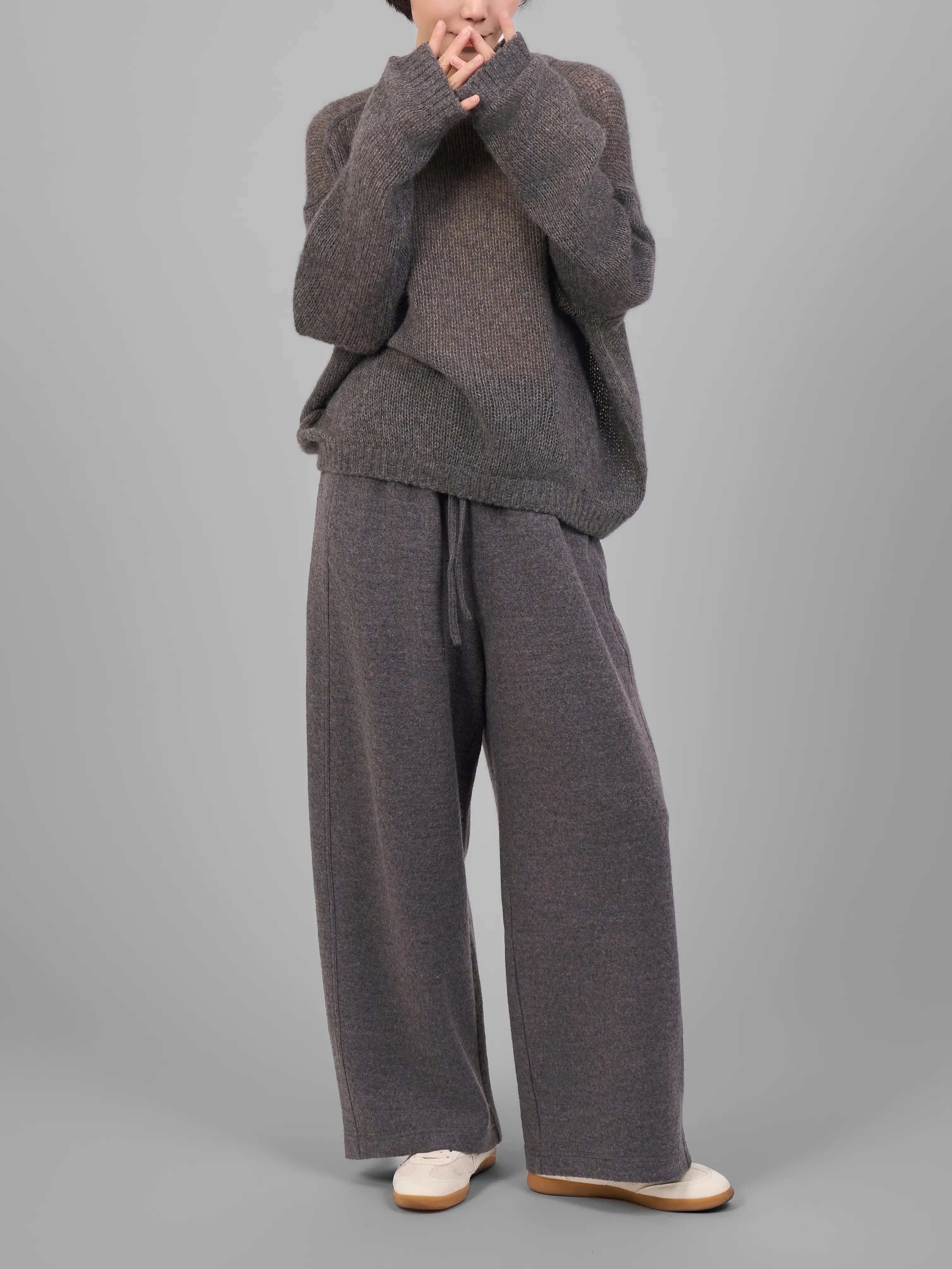 Model wearing grey cashmere-silk knit sweater and matching trousers in studio lookbook.