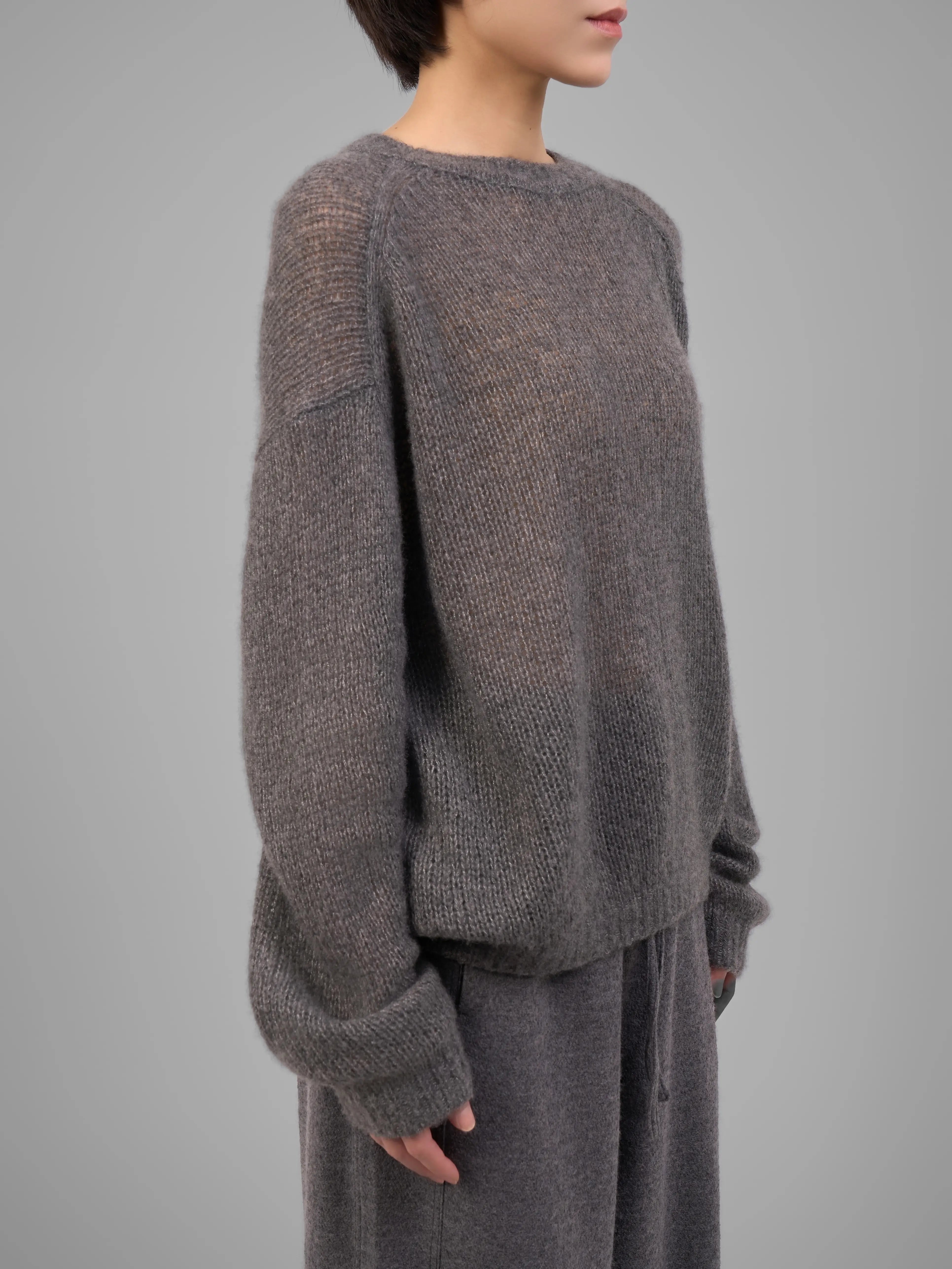 Model shown from the side wearing grey cashmere-silk knit sweater and trousers.
